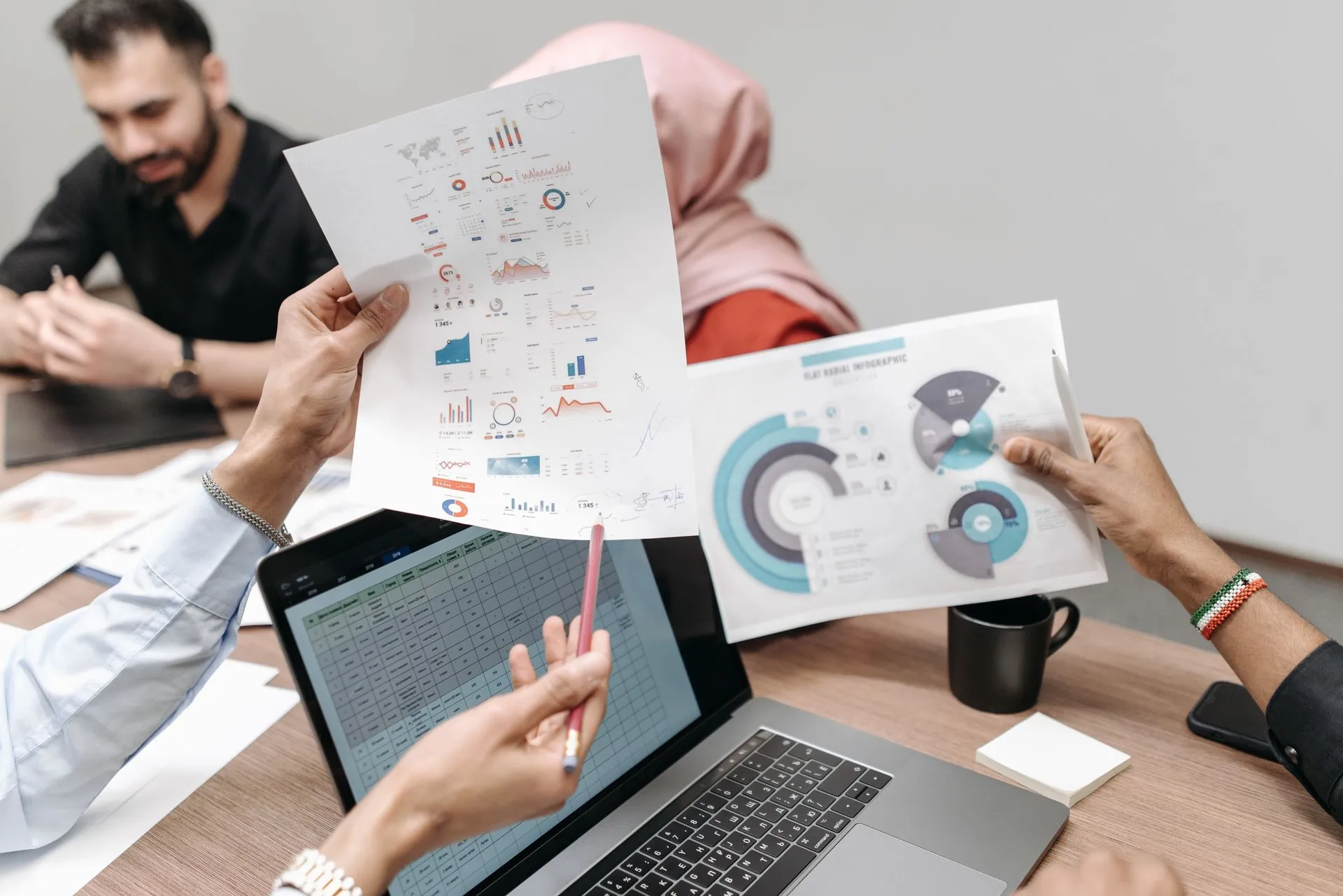Team analyzing graphs and data during a business meeting, showcasing hands-on engagement with paperwork and laptops, illustrating IBM launches Ready for SAP Solutions to speed midsize