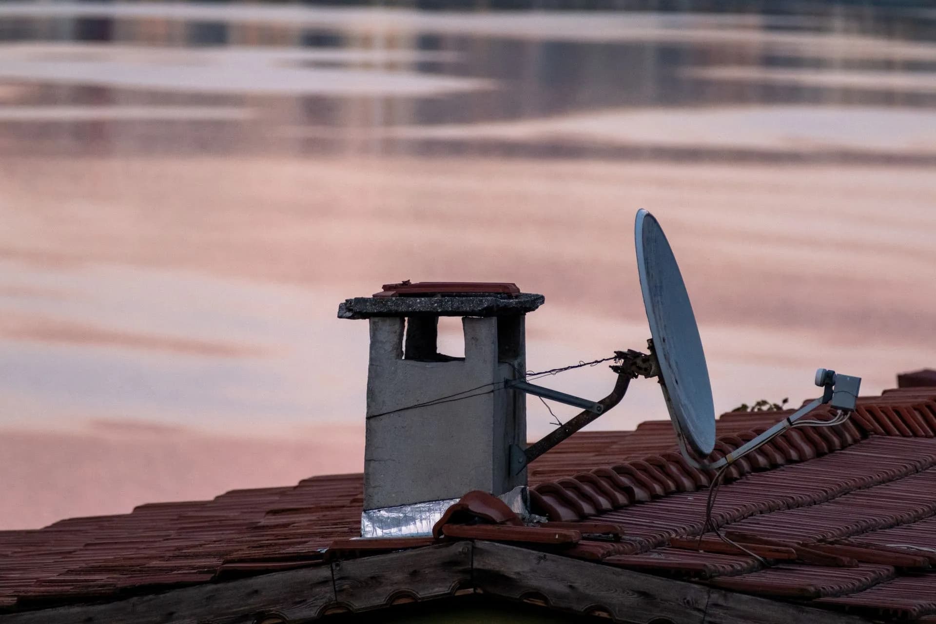 A close-up of a chimney and satellite dish on a rooftop during a serene dawn in Istanbul, Türkiye, illustrating India rejects Musk's Starlink discrimination claim, calling it baseless