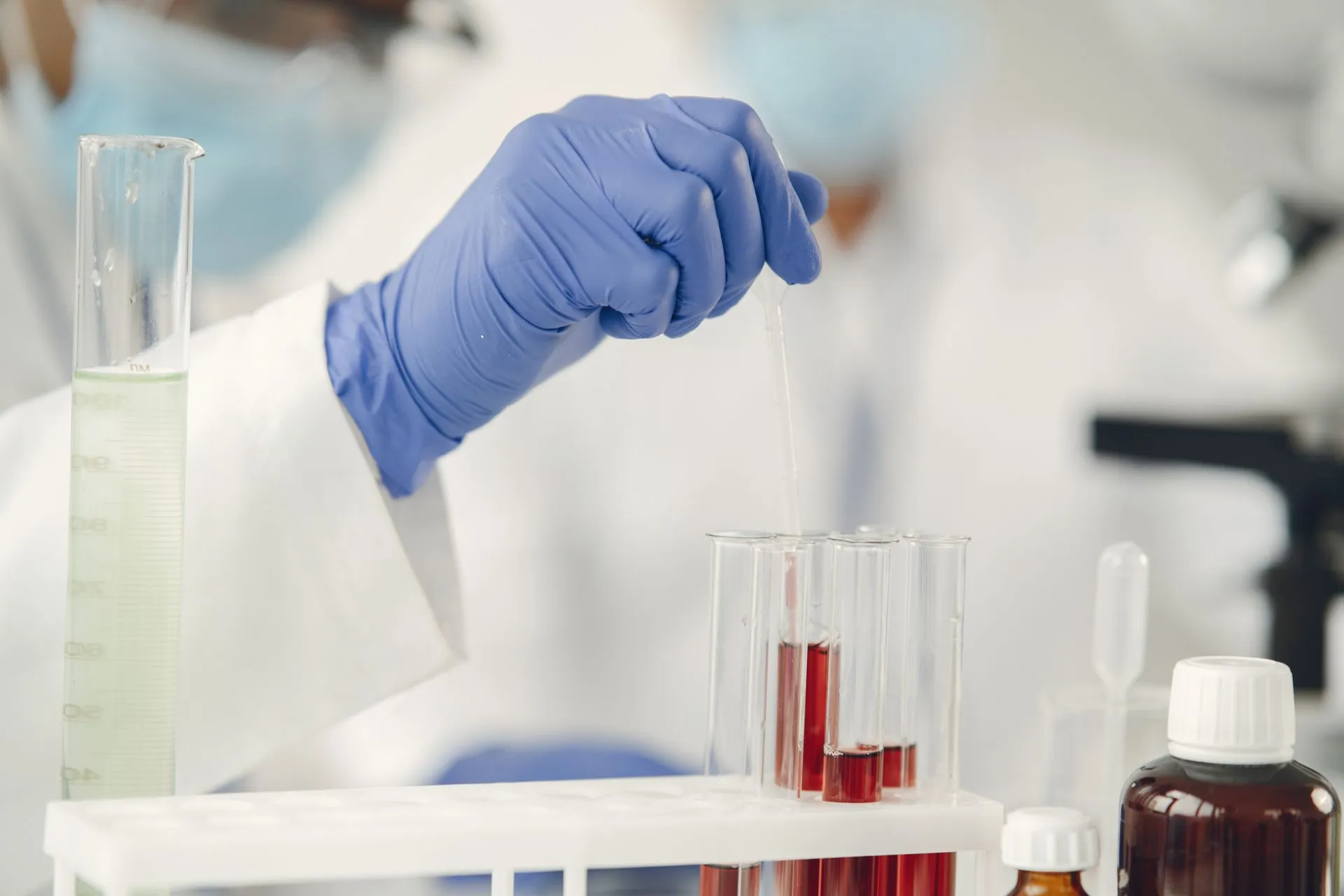Scientist in protective gloves conducting research with test tubes in a lab setting, illustrating Alphabet's Isomorphic Labs reportedly in talks to raise at a $40 billion to $50