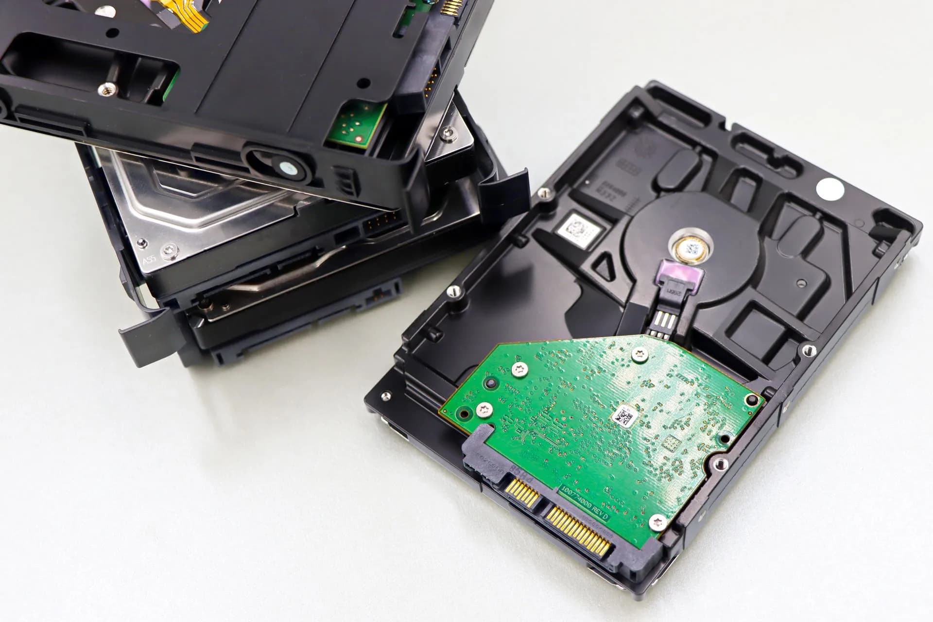 A collection of dismantled hard disk drives displayed on a white surface, showcasing internal components, illustrating JadePuffer Azure attacks used compromised cloud identities to
