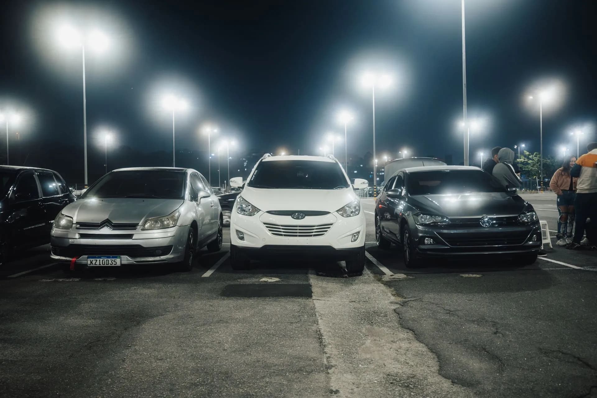 Night scene in a well-lit parking lot featuring various parked cars and street lamps, illustrating Times Car data breach affects 6.6 million accounts, Park24 says