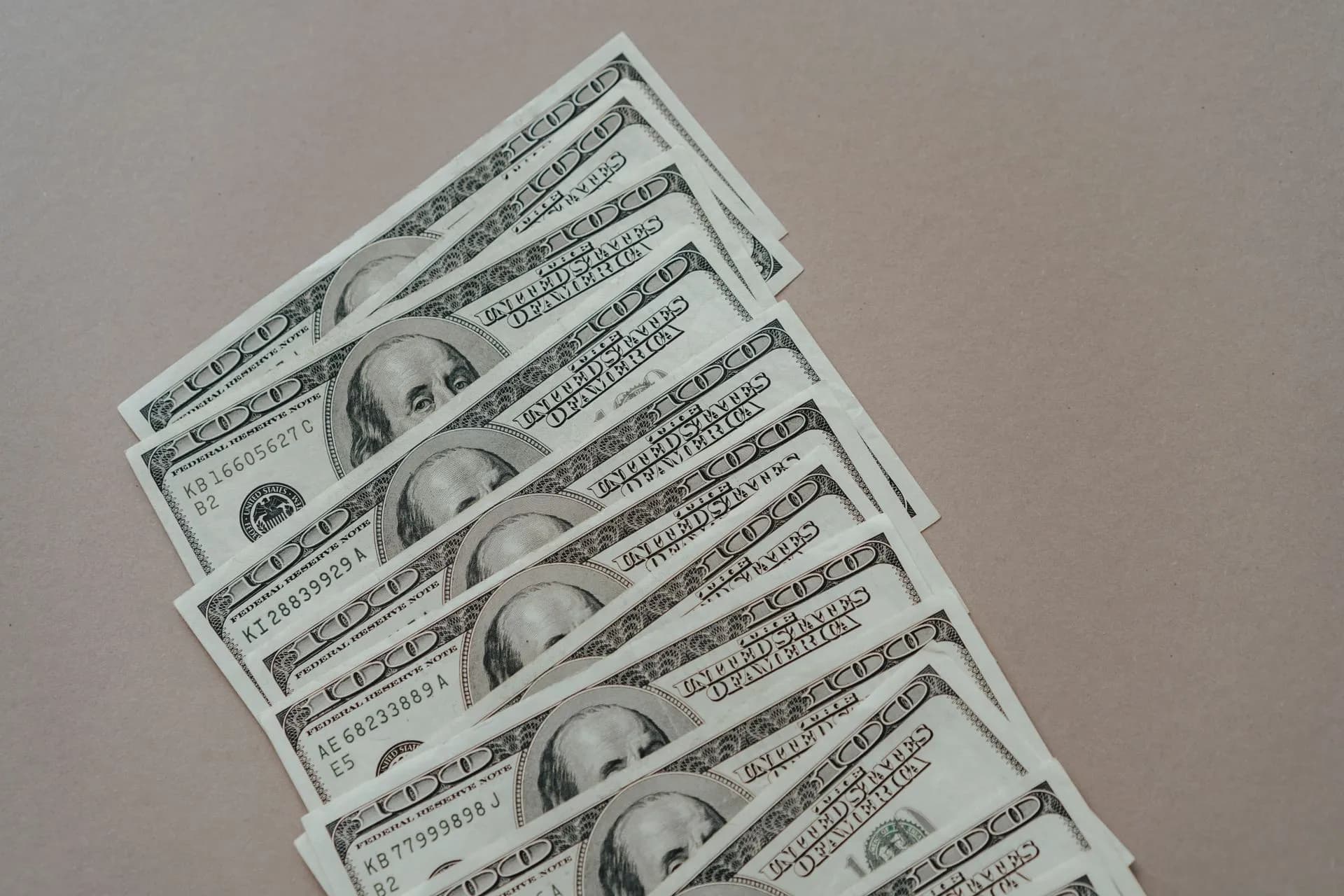 A close-up of multiple US dollar bills arranged on a neutral surface, illustrating Jumbo Series A rounds reach 114 deals worth $33 billion as investors crowd into AI