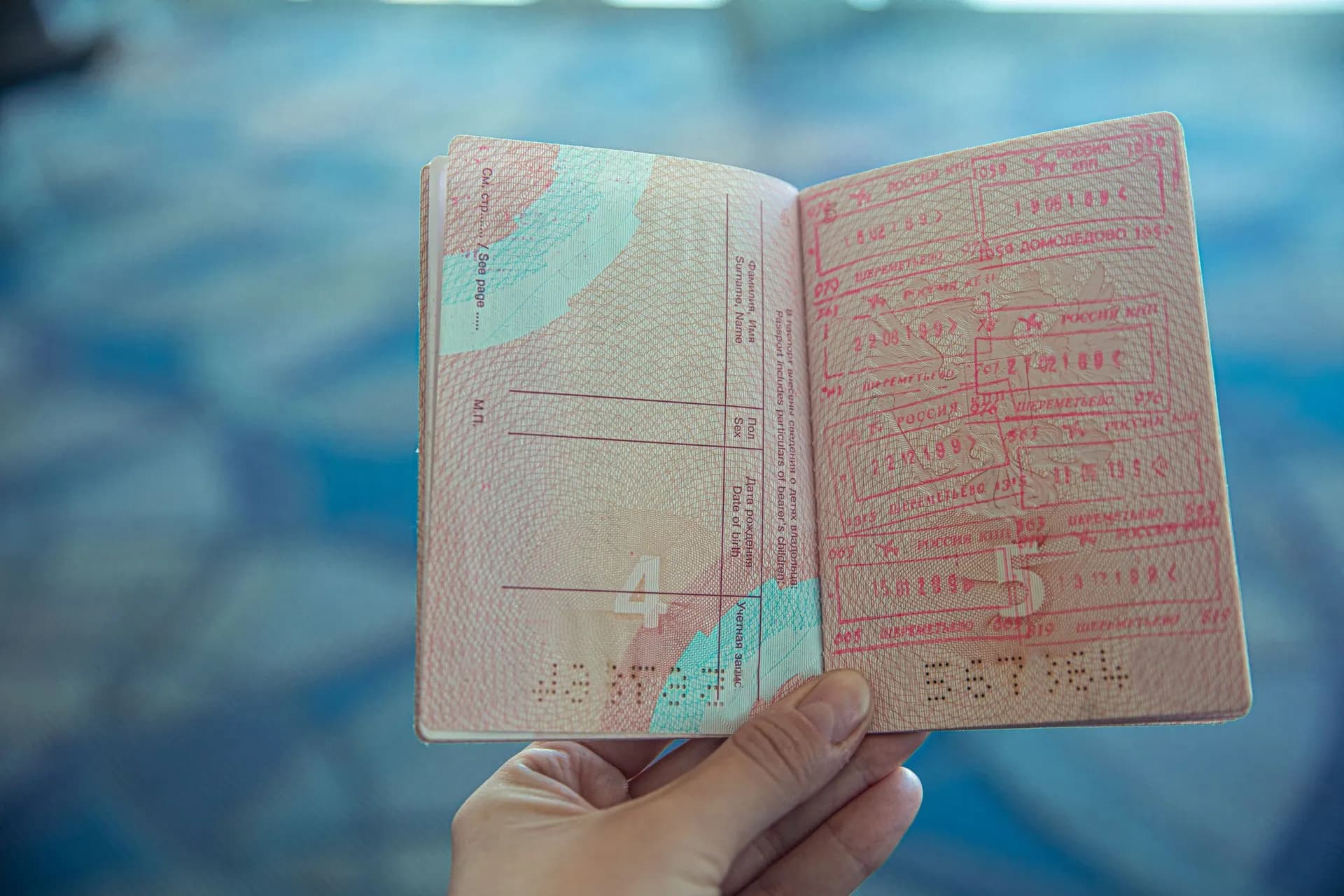 Close-up view of an open passport displaying various travel stamps in an airport setting, illustrating Labor Department suspends Microsoft, Adobe, Infosys and TCS from PERM labor