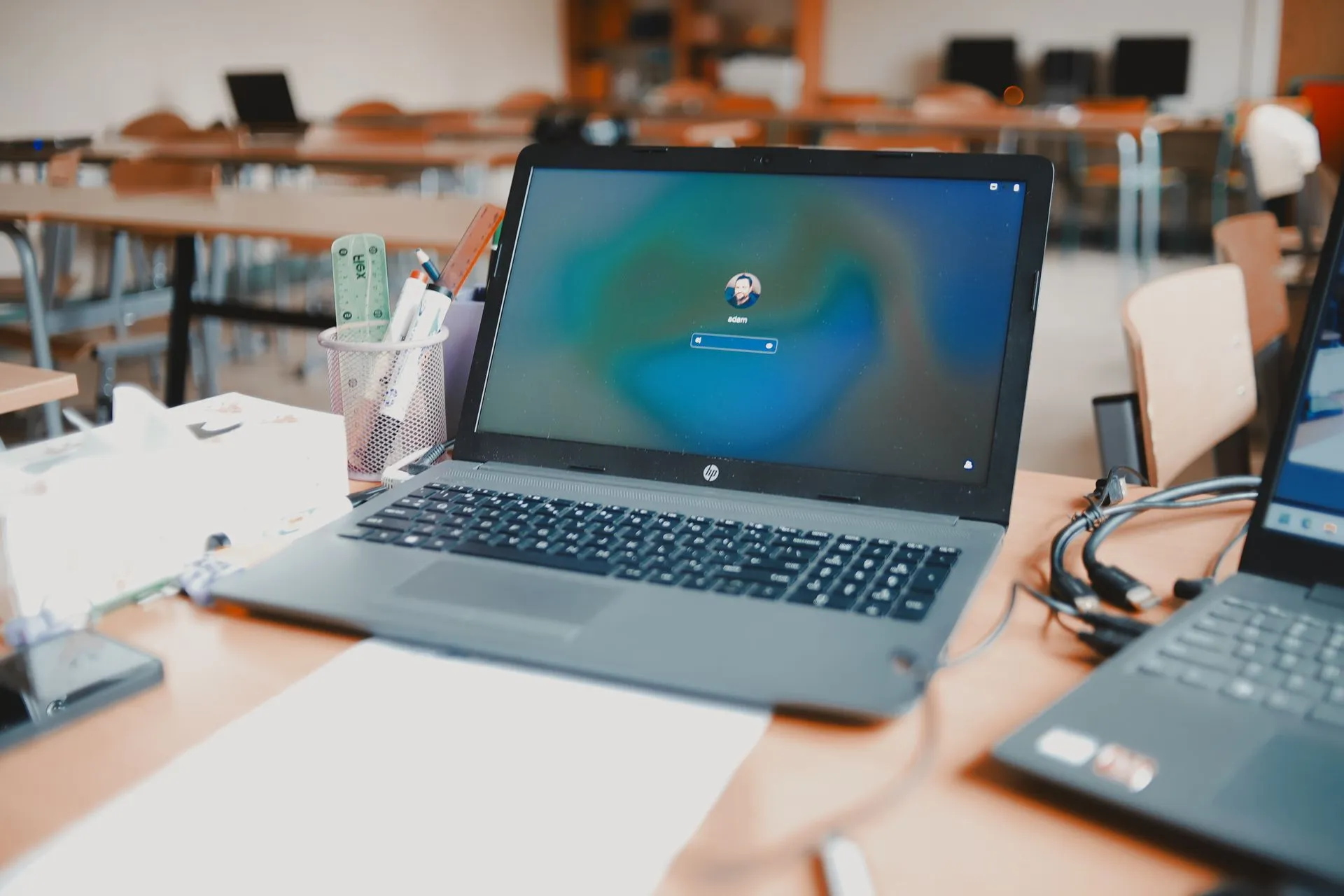A close-up of a laptop on a desk in a classroom setting, ready for educational use, illustrating LastPass Business Max will warn staff before they share sensitive data with AI tools