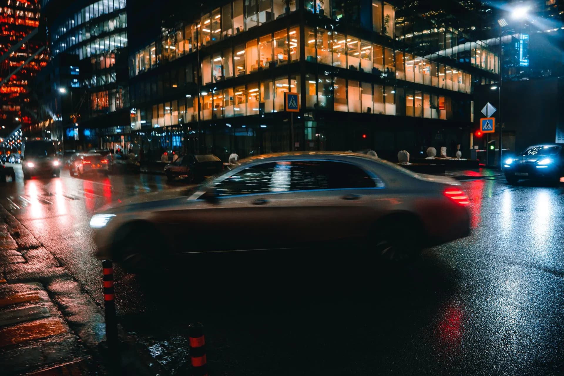 City street at night with cars and illuminated buildings reflecting on wet pavement, illustrating Lyft driver settlement
