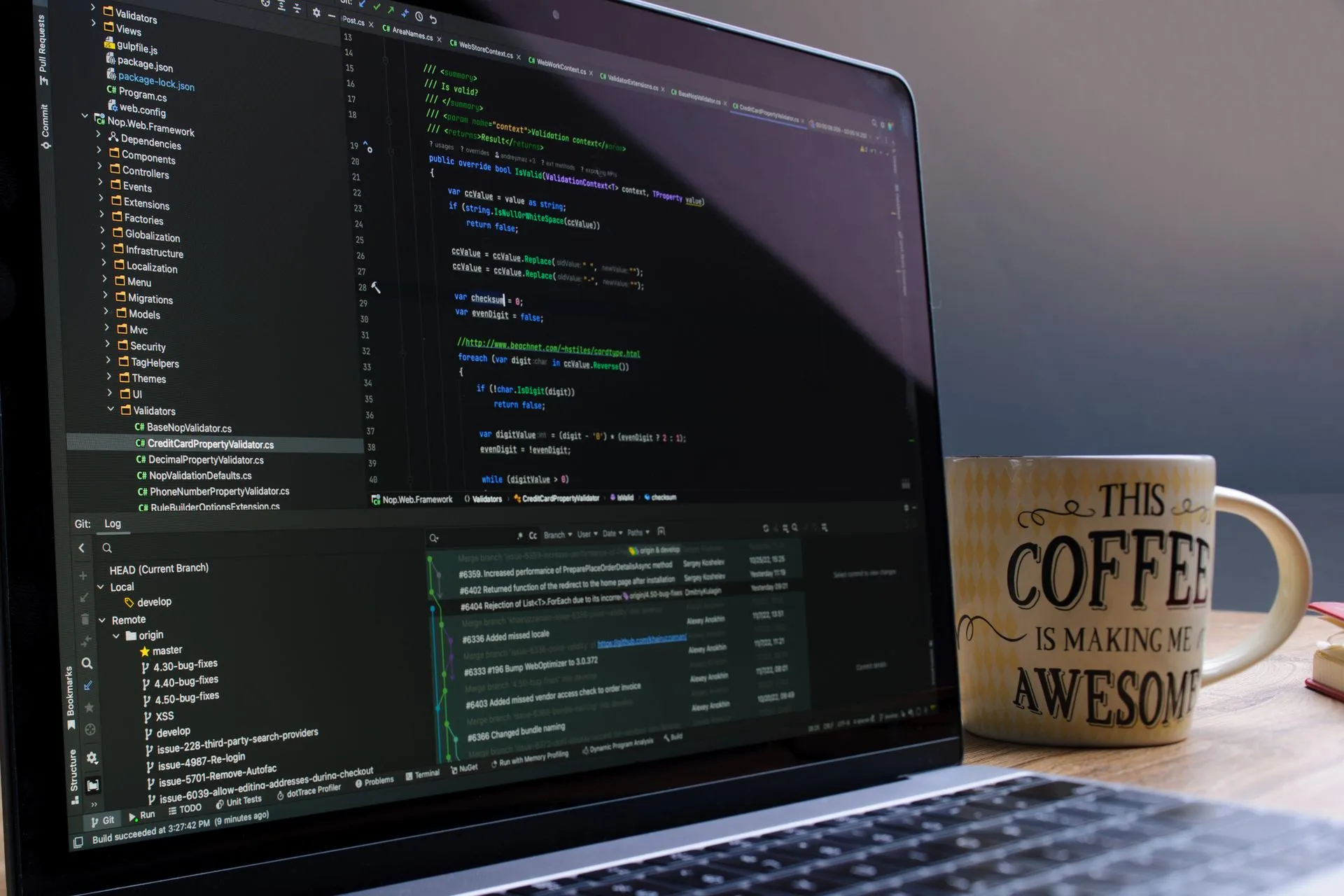 Close-up of laptop with coding software and a motivational coffee mug on a desk, illustrating Malicious npm packages