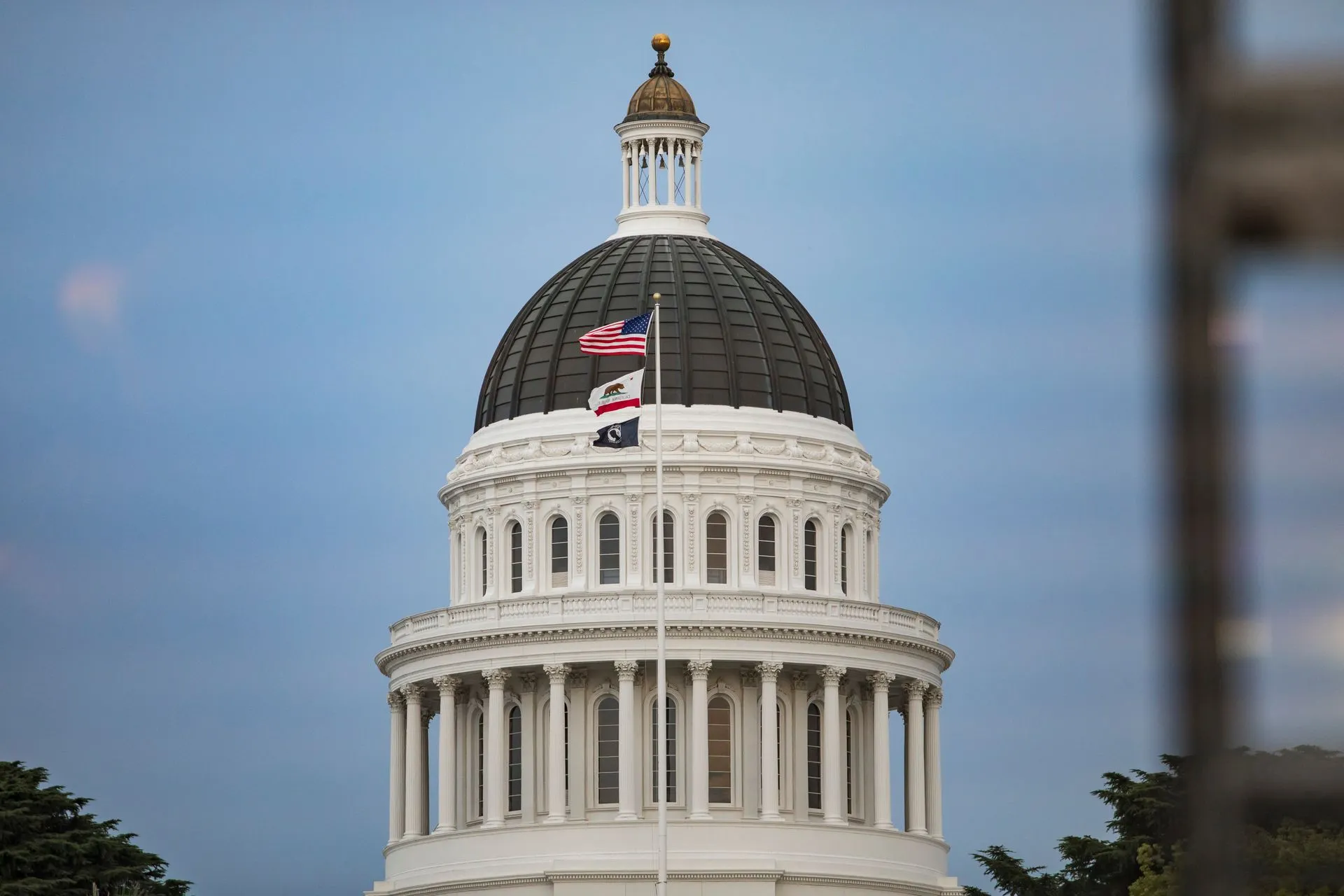 View of California State Capitol dome with American and state flags.