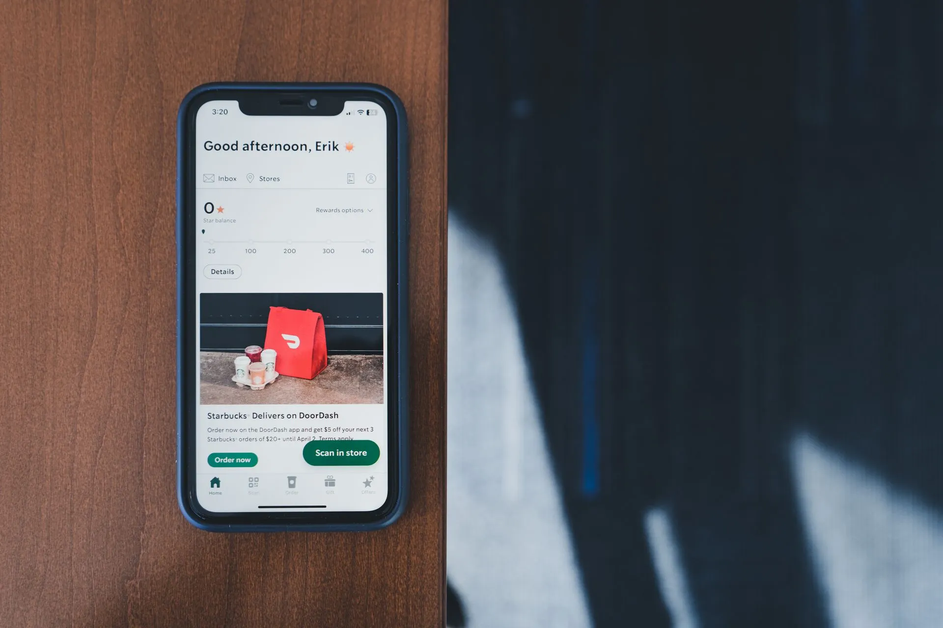 A smartphone displaying a shopping app screen placed on a wooden desk with natural light, illustrating YouTuber says Meta's Muse AI agent gave his home address to a stranger, who
