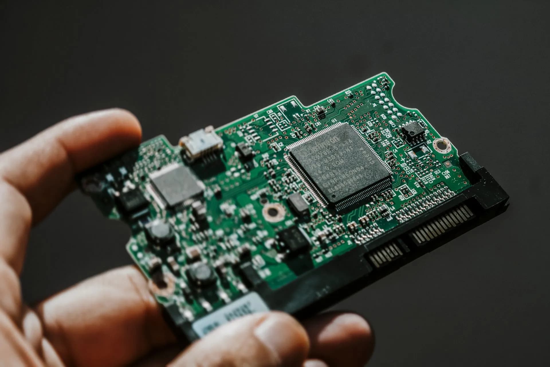 Close-up view of a green circuit board held by a hand, showcasing technology details, illustrating Meta open-sources Muse Gadgets code and gives away 5,000 Home Link devices