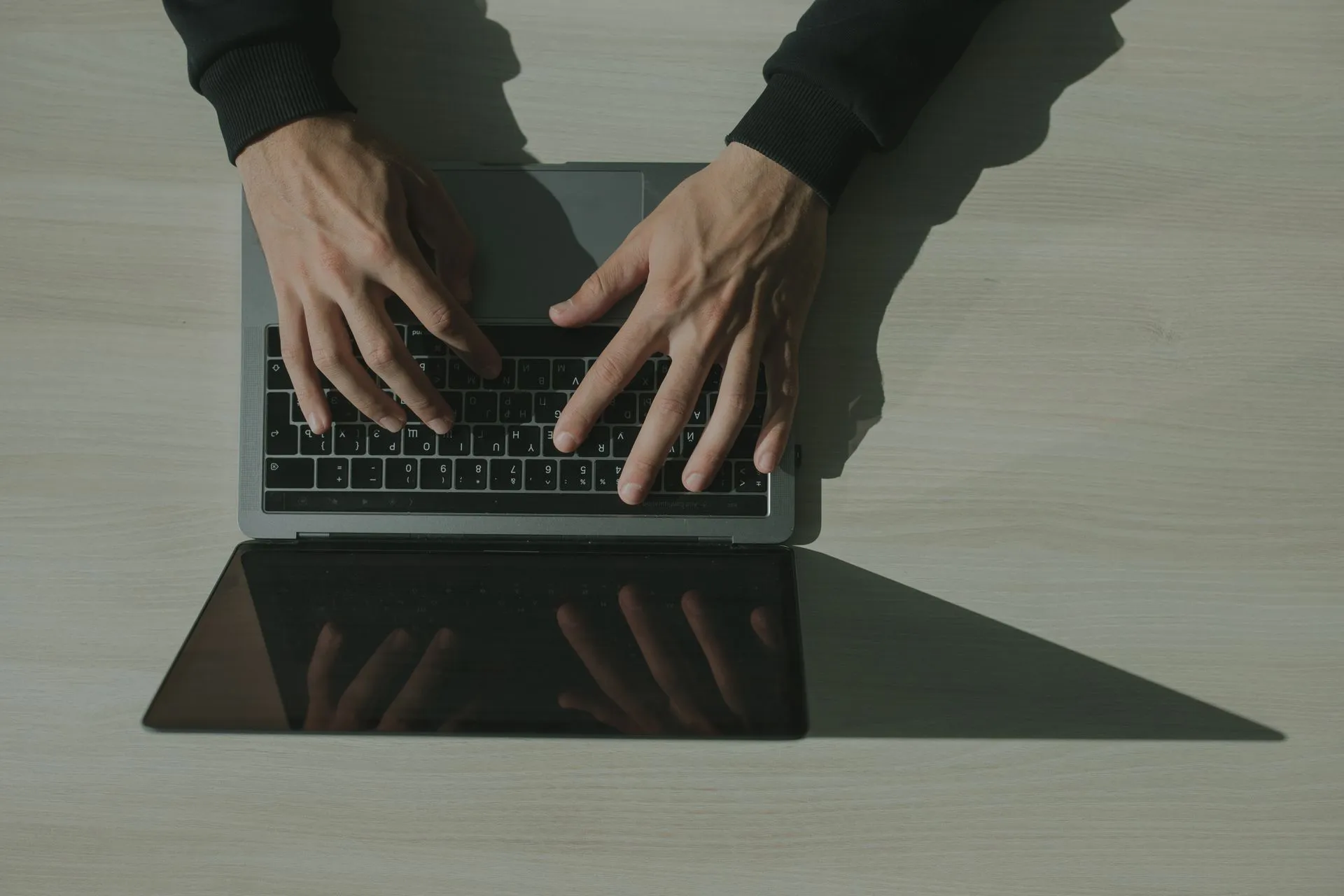 Overhead shot of hands typing on a laptop, showcasing technology and internet usage, illustrating Microsoft EvilTokens takedown hits AI phishing service tied to 12,000 hacked inboxes