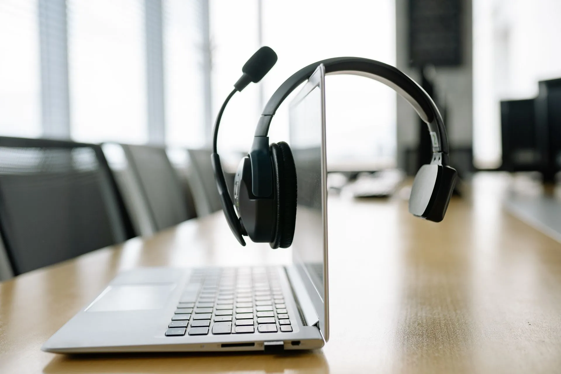 Sleek laptop with a wireless headset in a bright, modern office setting, illustrating Microsoft's MAI-Transcribe-2-Streaming targets voice agents at $0.54 per audio hour