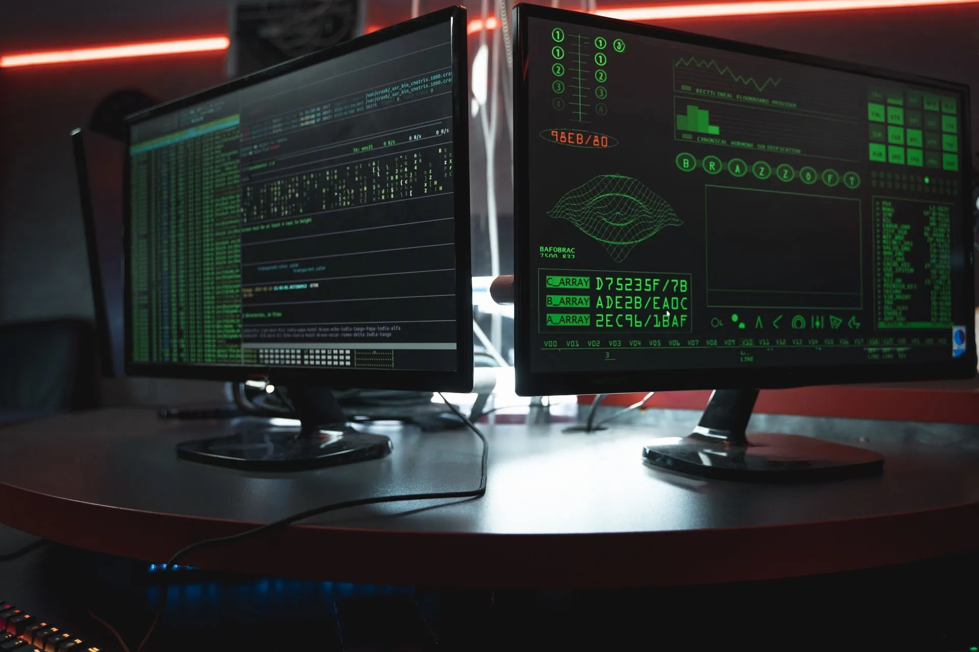 Close-up of dual computer monitors with green coding interfaces in a dark room, highlighting cyber security themes, illustrating Microsoft details NeedyMantis malware found while probing