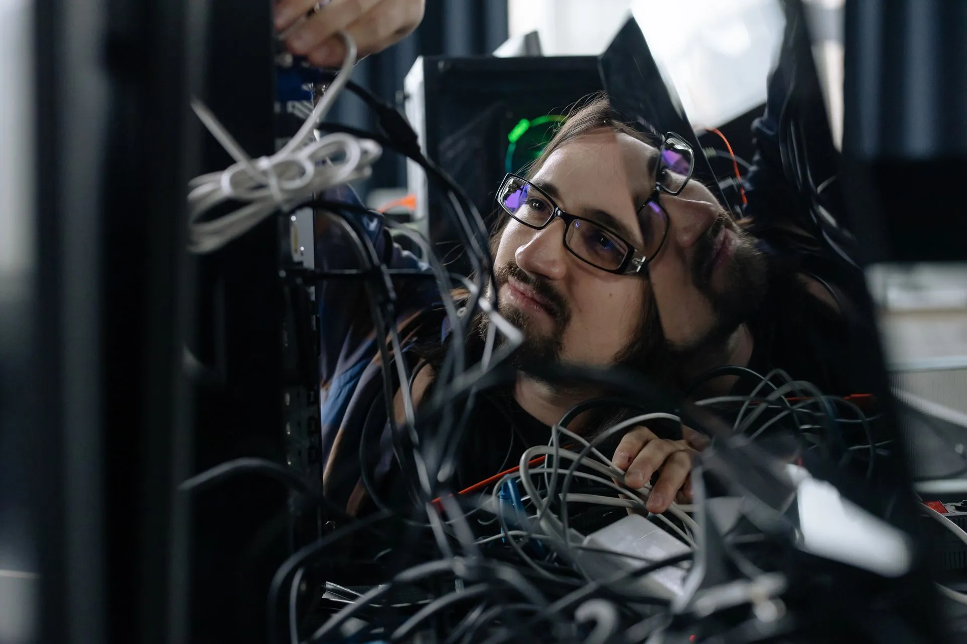 A skilled IT technician organizing tangled cables at his workstation in an office environment, illustrating MongoDB buyback rises to $2 billion, disclosed a day after its CEO left for