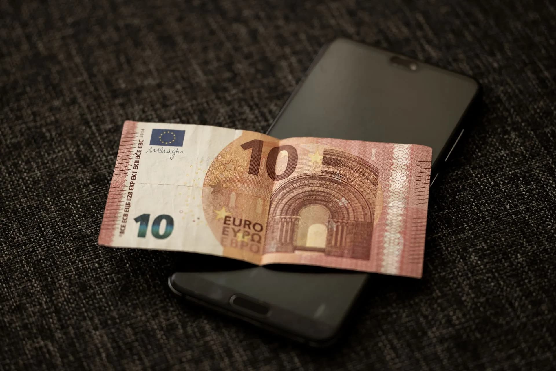 A close-up shot of a 10 euro banknote placed on a smartphone, highlighting currency and digital technology, illustrating Mynt IPO prices at P6.60 a share, valuing GCash parent at about