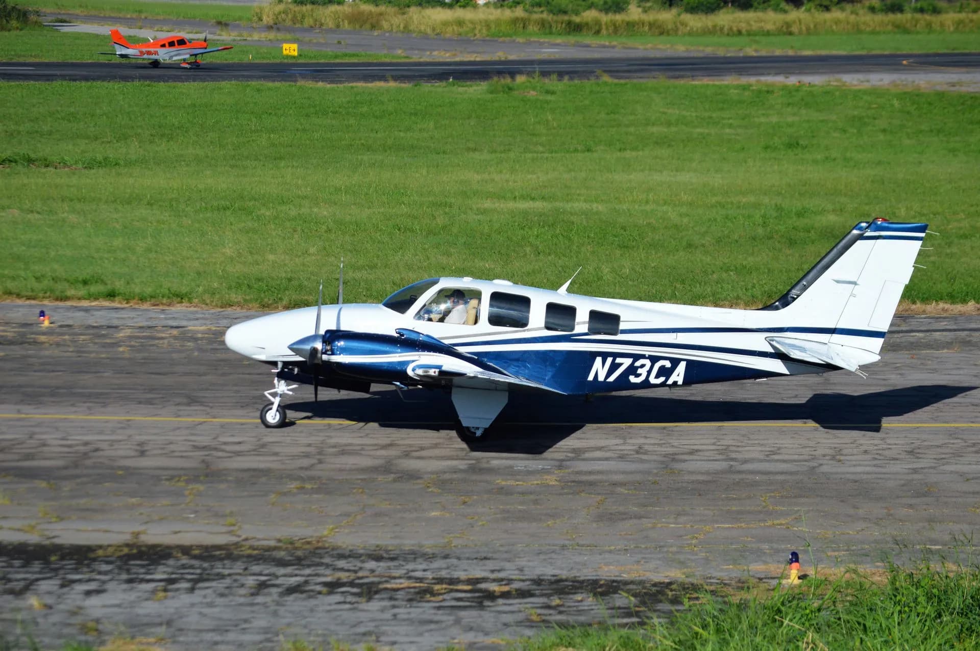 A small aircraft with registration N73CA taxiing on a sunny runway with green grass, illustrating Nimbus Aerospace flies quarter-scale hybrid-electric aircraft prototype in Oregon