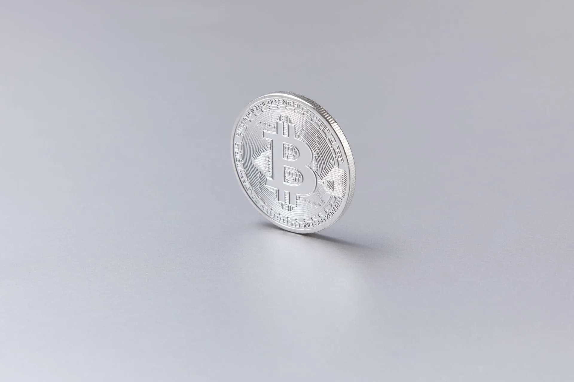 Close-up of a silver Bitcoin coin standing upright against a clean, white background, illustrating Noah closes $38M seed round for stablecoin payment rails, says revenue rose 538%