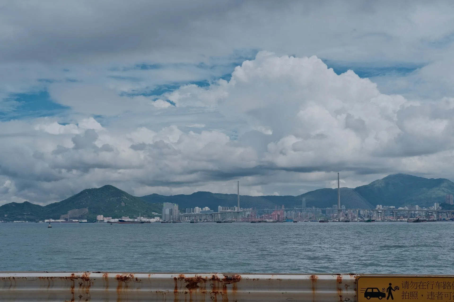 Dramatic cityscape with ocean and mountains under cloudy sky, illustrating HSBC names HK$ RedCoin, StraitsX plans XSGD on Monad as non-dollar stablecoins gain ground