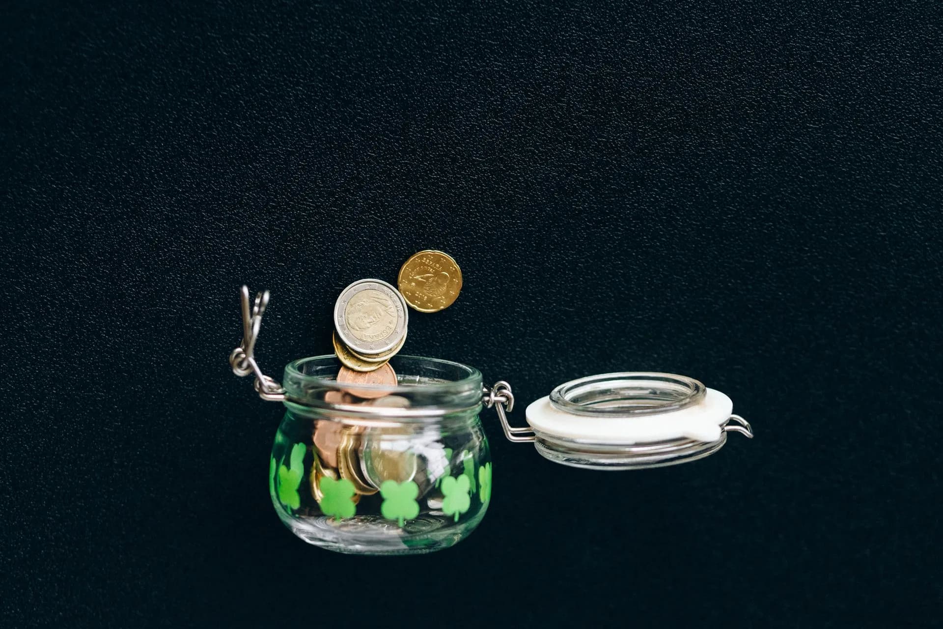 Glass jar with coins falling into it on a black background, symbolizing savings, illustrating Nubank US launch pays 3.5% on savings through Lead Bank, with a 4.5% tier coming soon