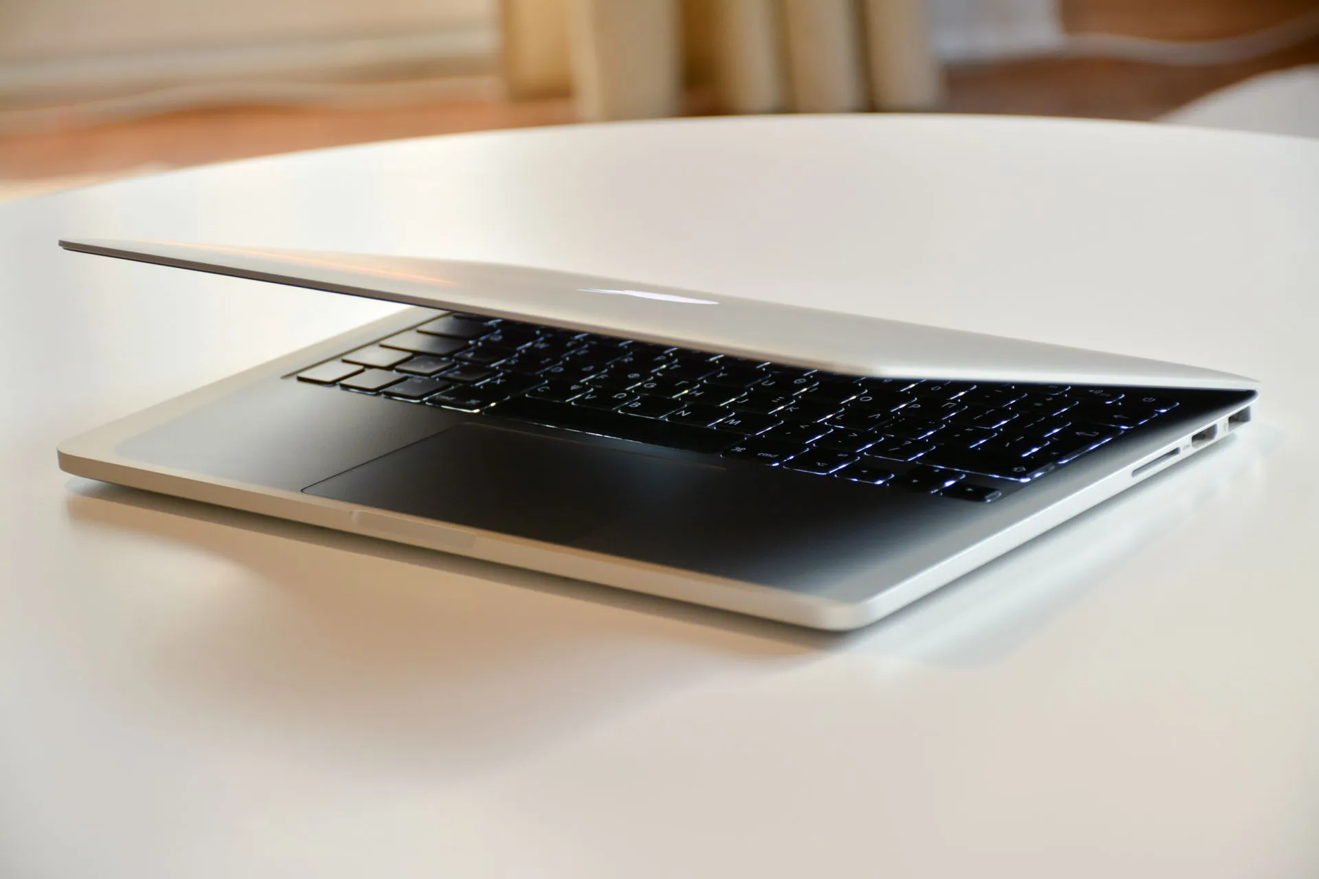 A modern MacBook laptop with a sleek design, slightly closed on a white table indoors, illustrating Nvidia RTX Spark Windows PCs launch