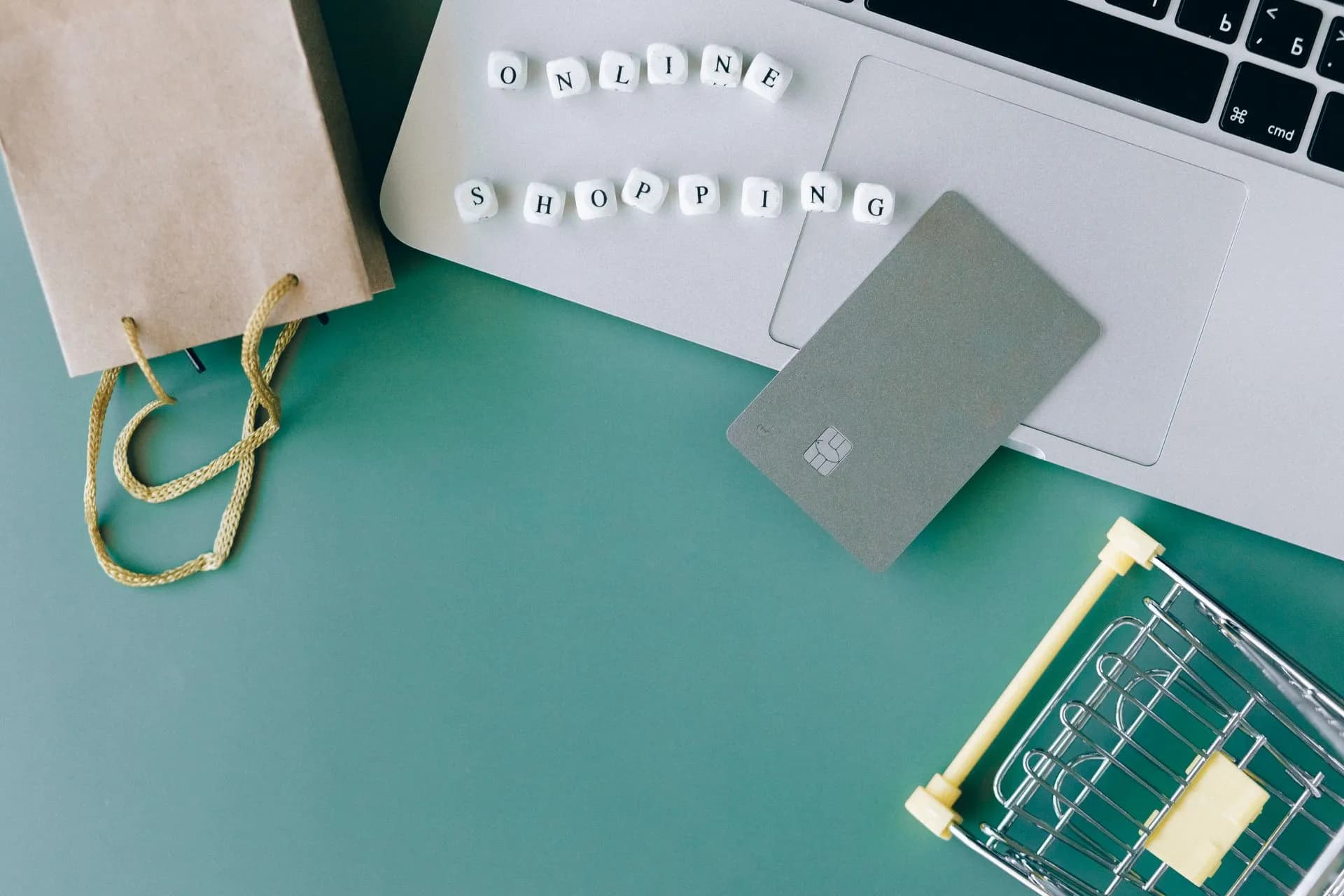 Flat lay of online shopping essentials with laptop, card, and shopping cart, illustrating New York City click-to-cancel rule takes effect, with penalties starting at $525