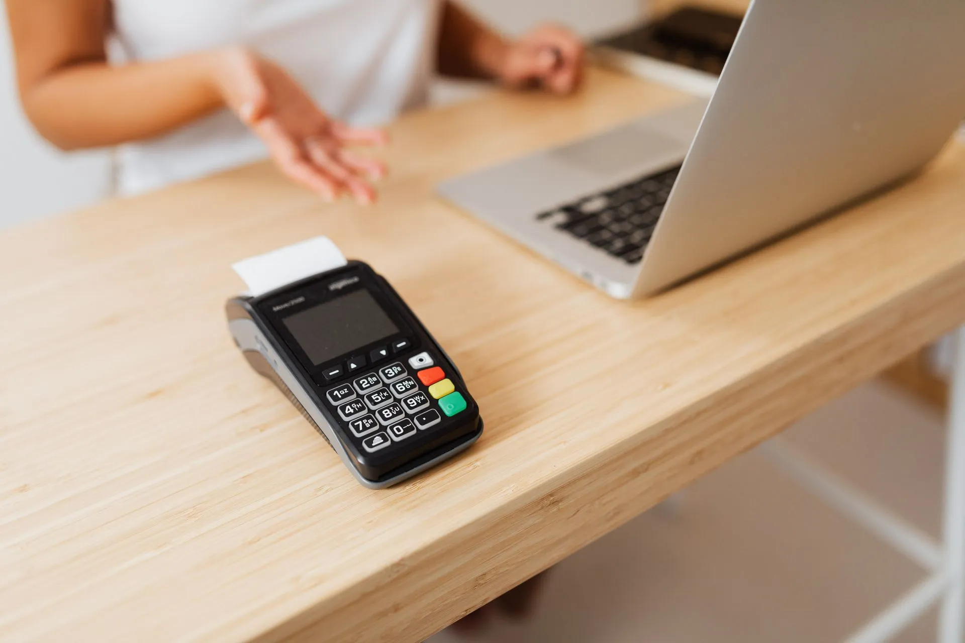 Close-up of a card reader on a wooden desk ready for contactless payment, illustrating OpenAI and America's SBDC announce AI training pilot for 1,000+ small businesses