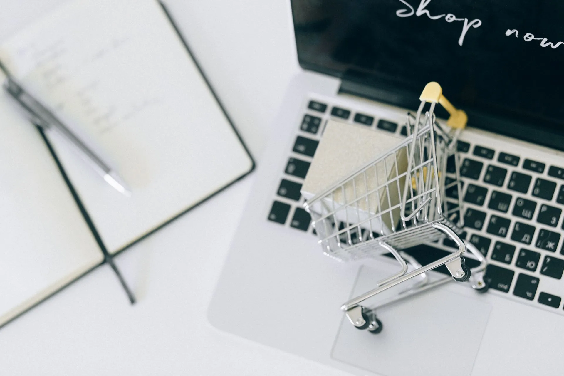 Creative depiction of online shopping with a miniature cart on a laptop keyboard, illustrating OpenAI Marketplace turns AI commitments into software budgets for 30-plus apps