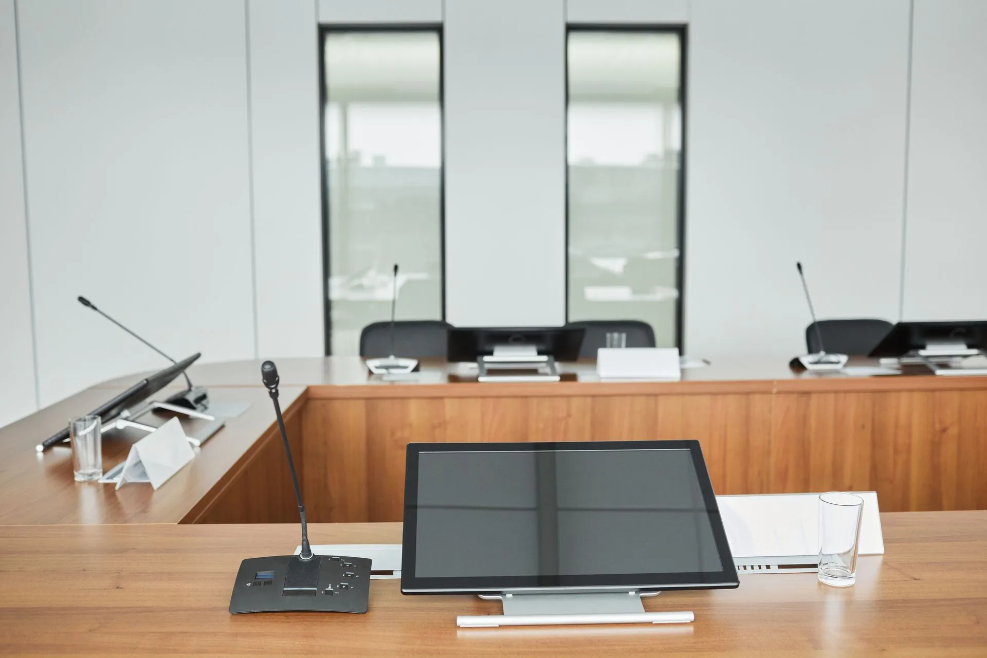 Empty conference room setup with microphones, monitors, and sleek wooden tables ready for meetings, illustrating OpenAI safety turmoil