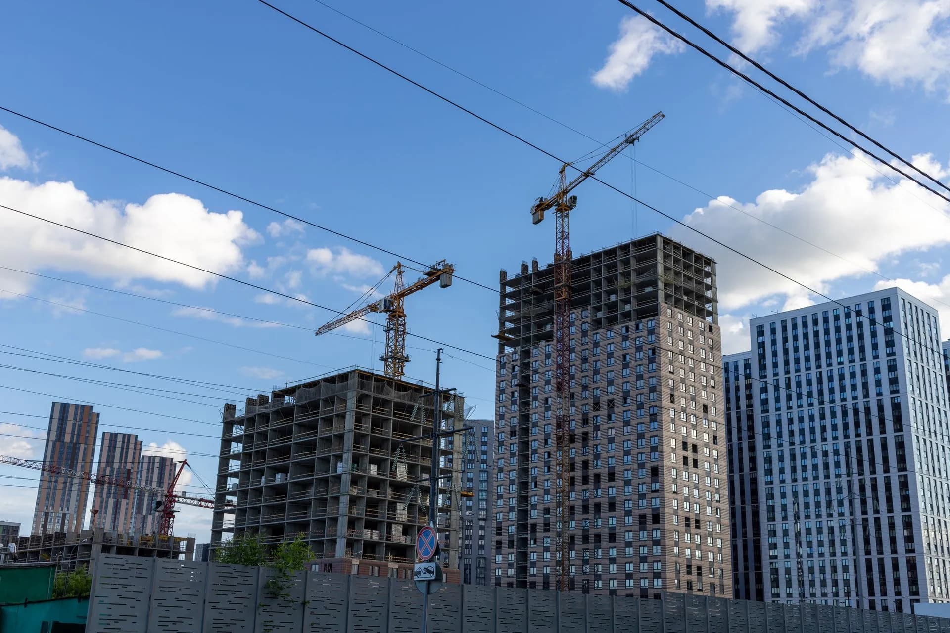 City skyline with modern buildings and construction cranes under a blue sky, illustrating Oracle's $664 billion backlog will take years to become revenue, a timing test for AI cloud