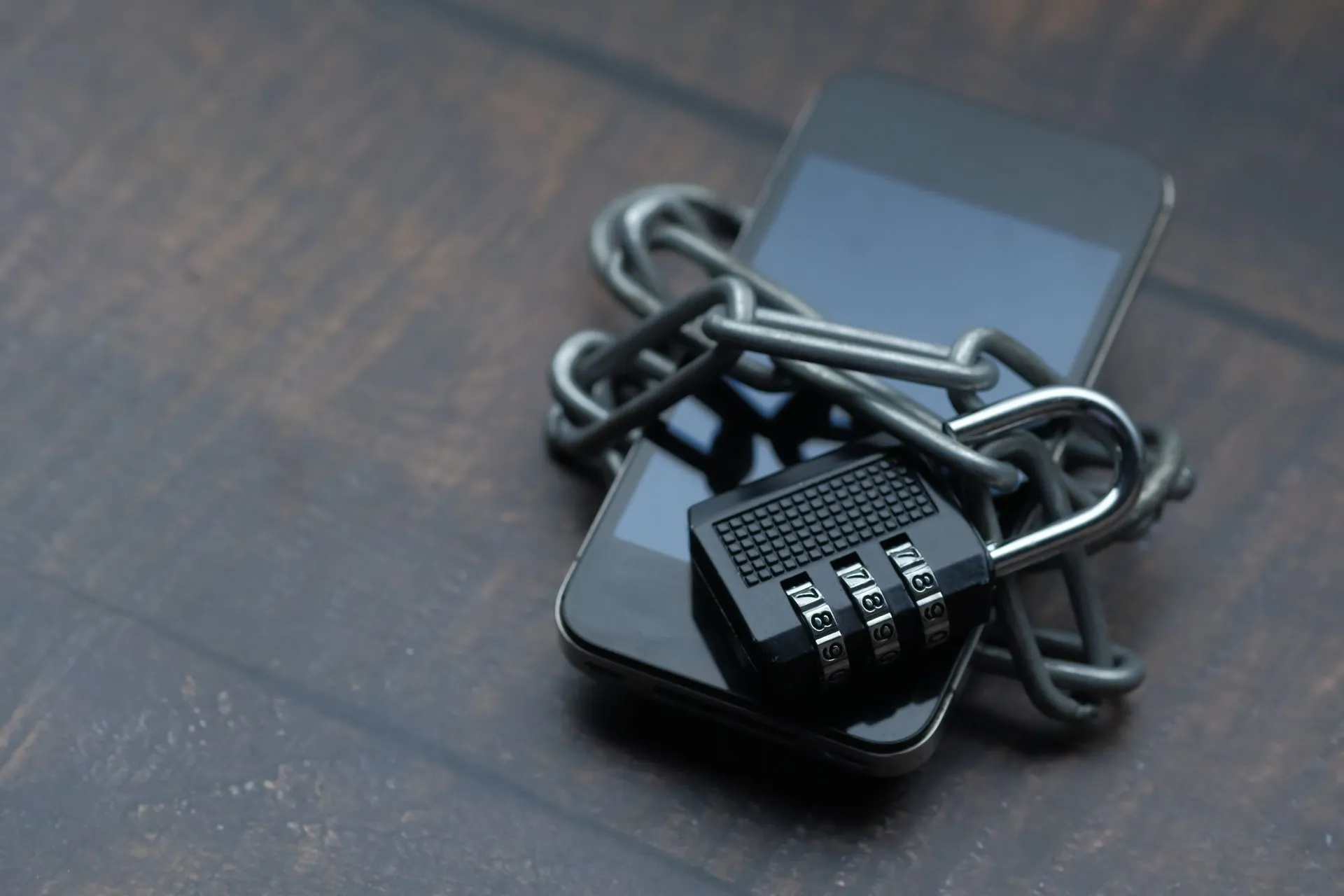 Close-up of a smartphone wrapped in a chain with a padlock, symbolizing strong security, illustrating Spyware maker Paragon's parent REDLattice plans Nasdaq listing in $1.25 billion