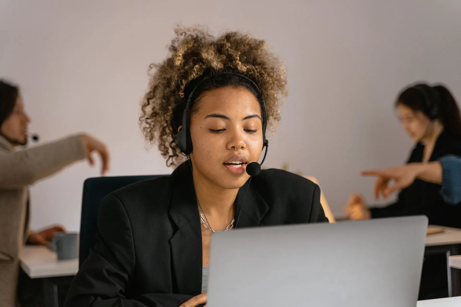 Customer support agent with headset working on laptop in office, illustrating Plaid brings bank account access to Decagon AI agents inside customer support chats