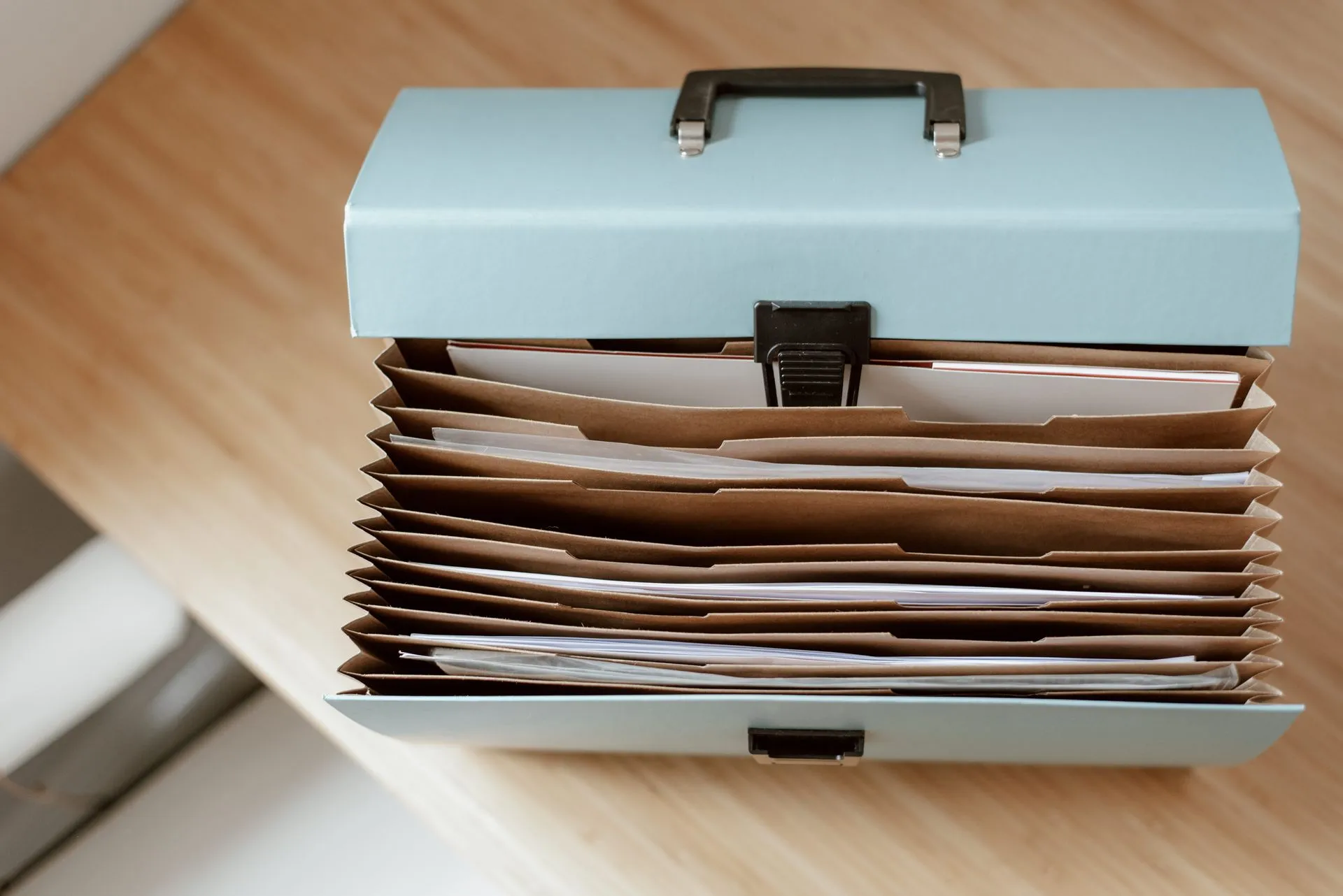 From above of briefcase for documents with papers placed on wooden table in daytime, illustrating Progress launches ShareFile Enterprise with DLP that can block sensitive file downloads