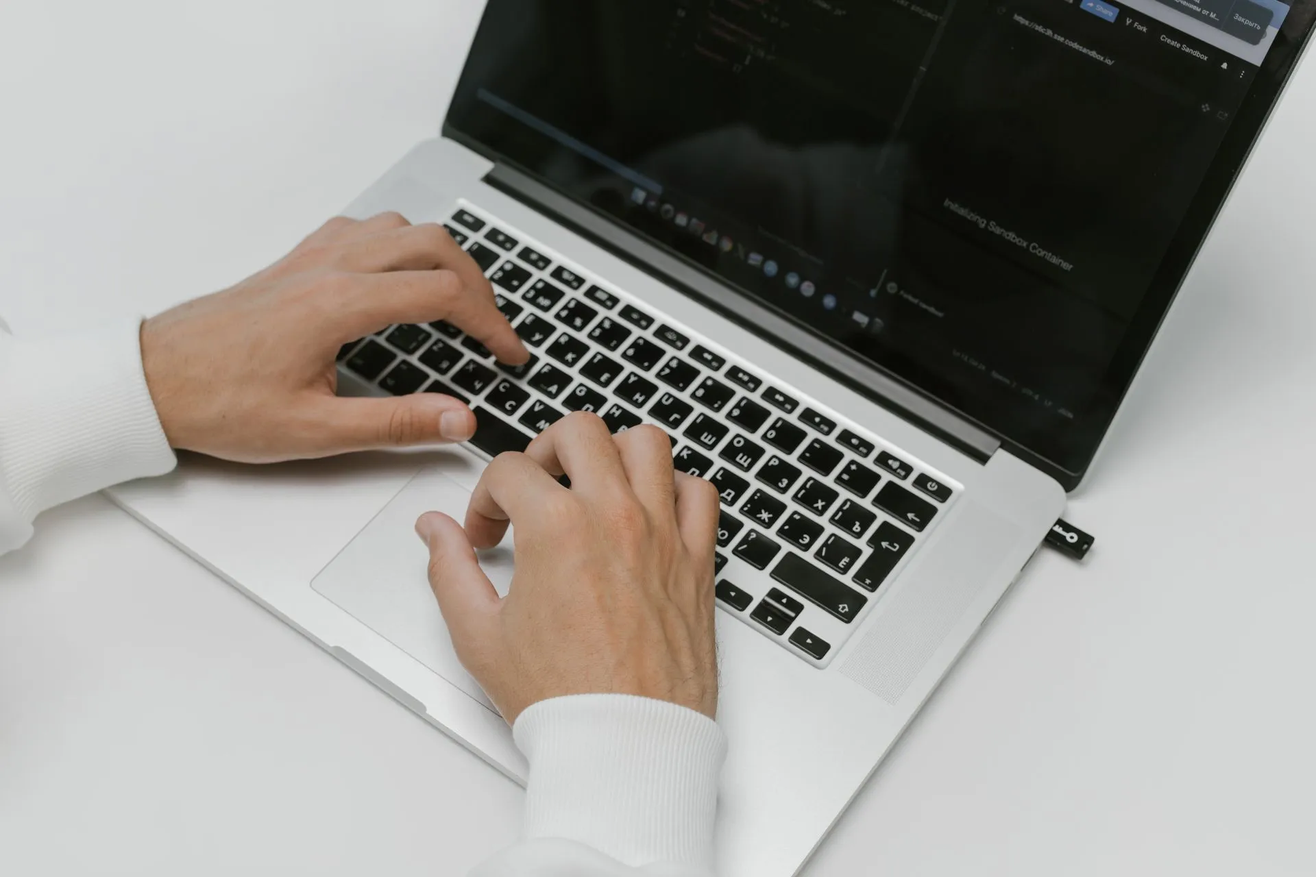Close-up of hands typing on a laptop with a USB device on a white background. Ideal for tech and cybersecurity themes, illustrating Proofpoint ties China-aligned TA419 to phishing that