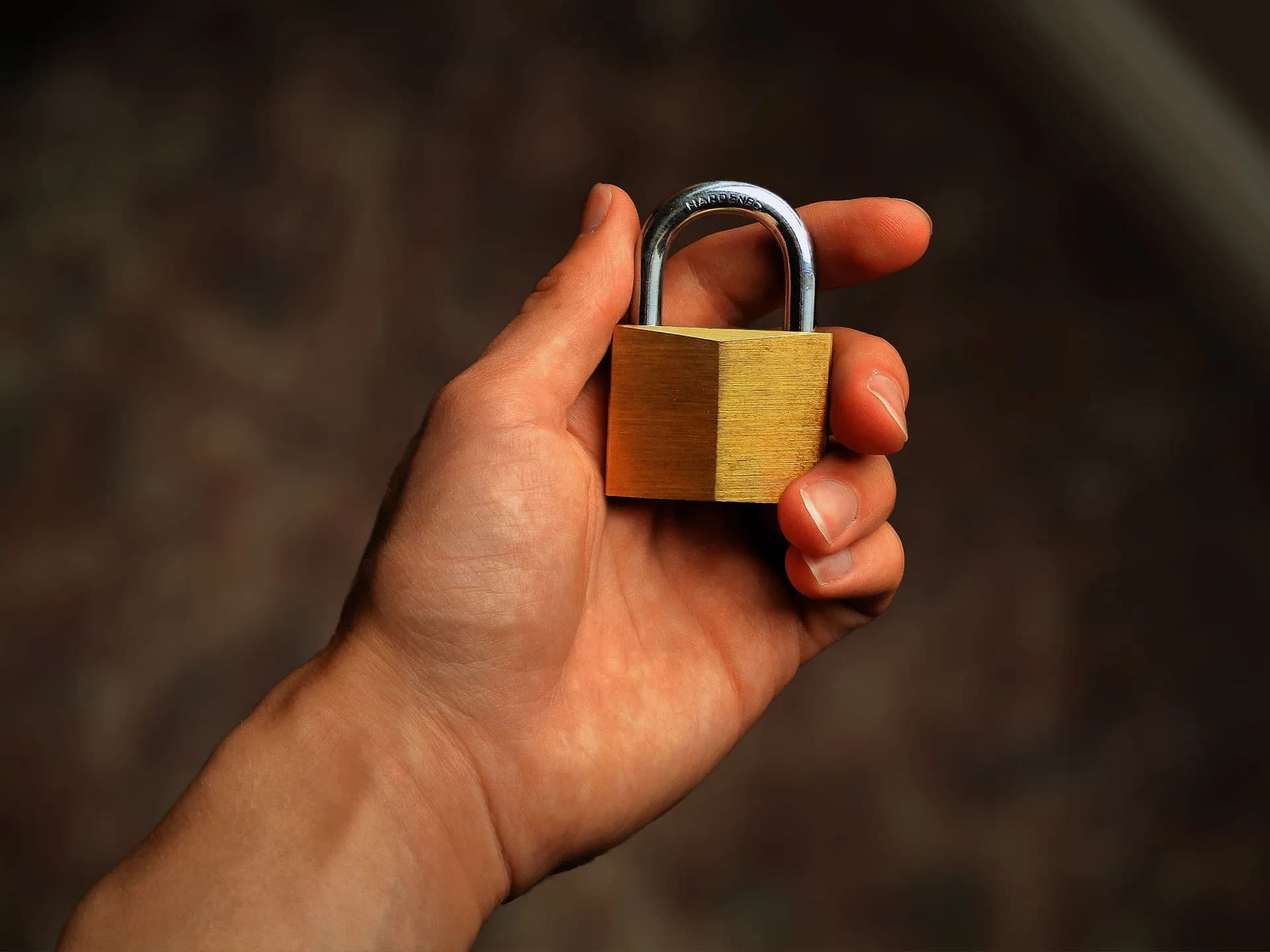 Hand holding a brass padlock, symbolizing security and protection, illustrating Reco raises $55 million for AI agent security, says one client had 21,000 unknown agents