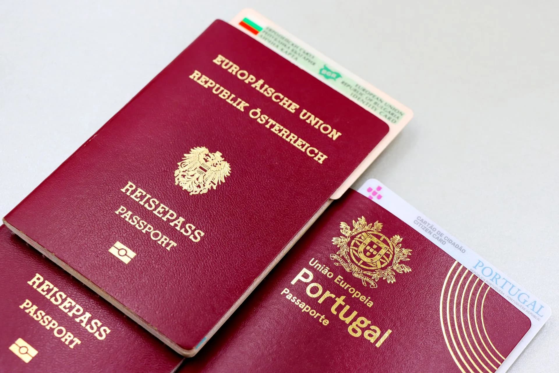 A close-up image of Austrian and Portuguese passports with a Bulgarian ID card, illustrating Revolut to pay for new IDs after 680-customer data leak as neobank fraud costs climb