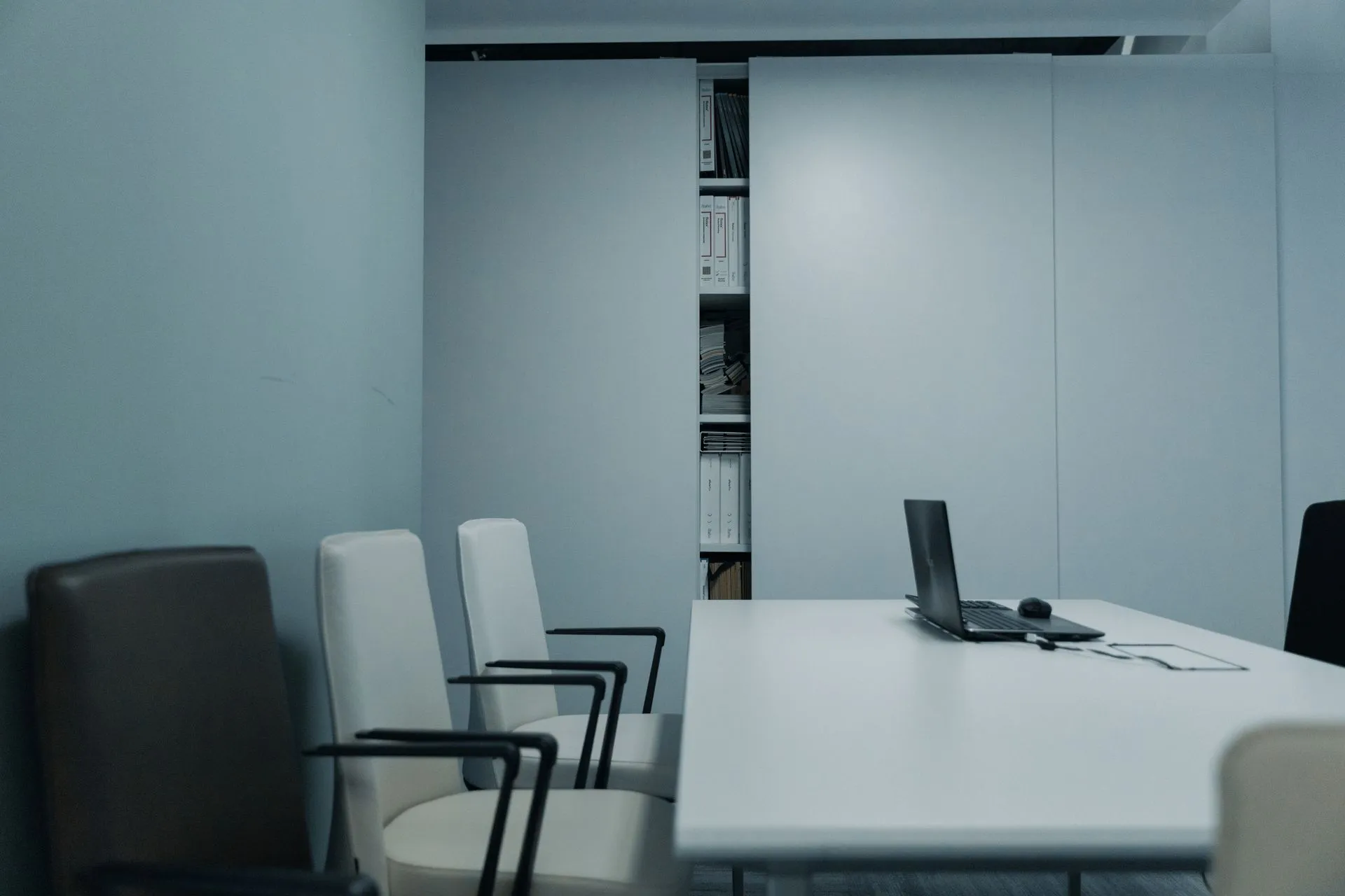 A sleek conference room with a white table and chairs, featuring a laptop on the table, illustrating Ryan Roslansky, Microsoft's LinkedIn and M365 chief, to leave after nearly 18 years
