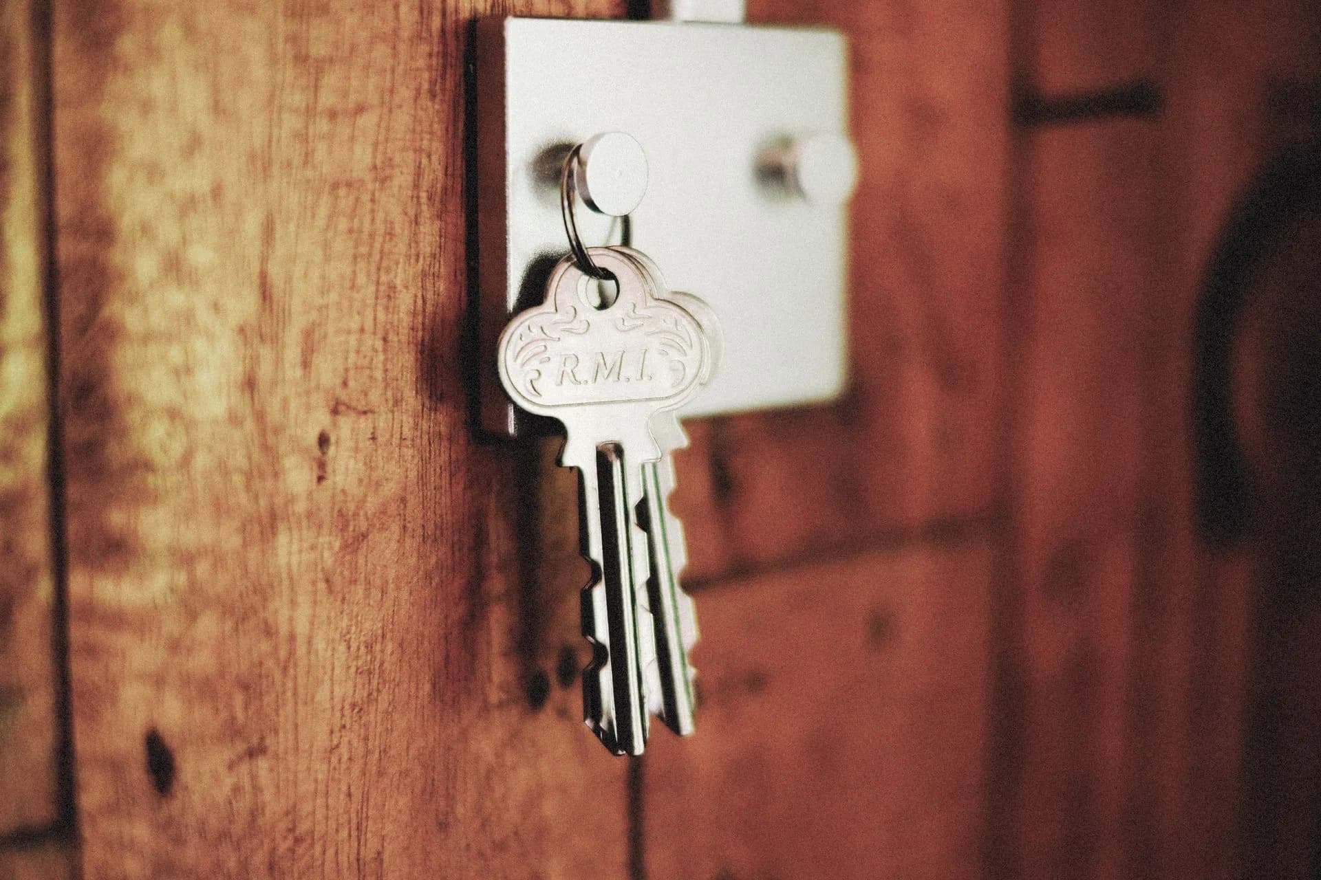 Detailed shot of keys hanging in a door lock on a wooden surface, warm tones, illustrating SAIC acquires Information Security Corporation to add post-quantum encryption tools