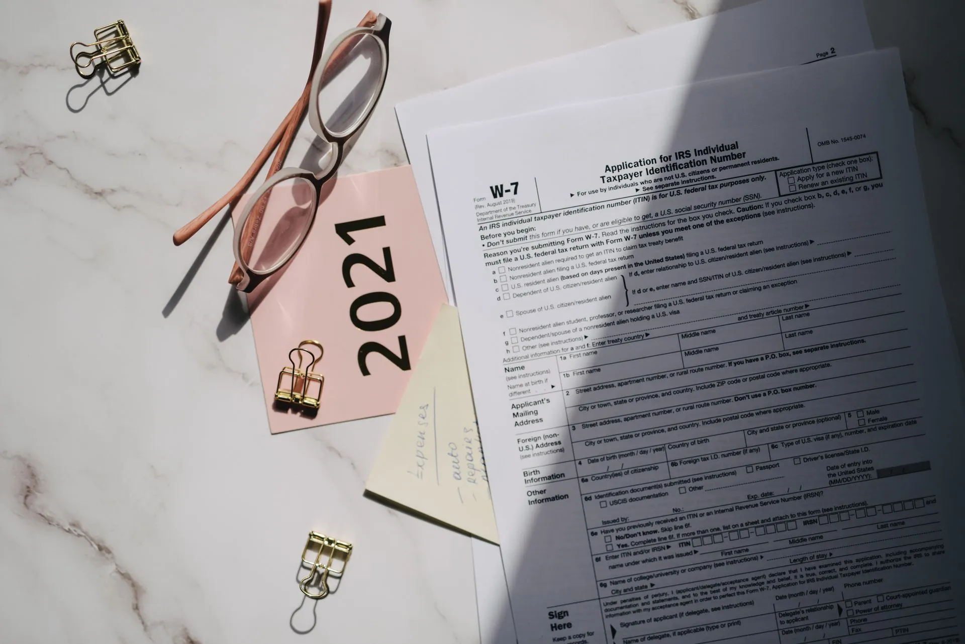 Flat lay of IRS tax documents with reading glasses and 2021 note on a marble surface, illustrating SEC exam handbook spells out 180-day and 30-day deadlines for advisers and brokers