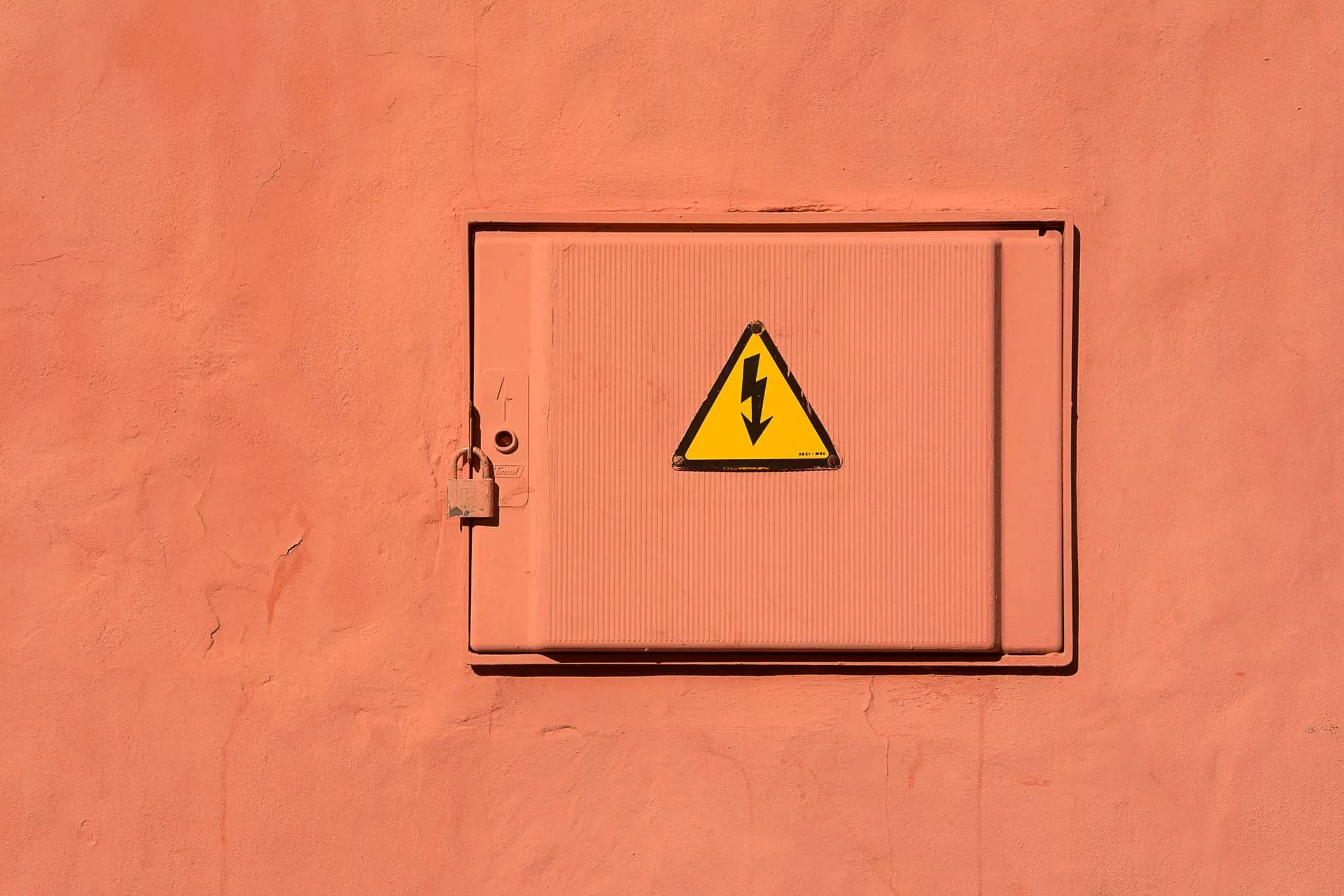 Bright yellow high voltage warning sign on a locked electrical box, illustrating Self-hosted AI