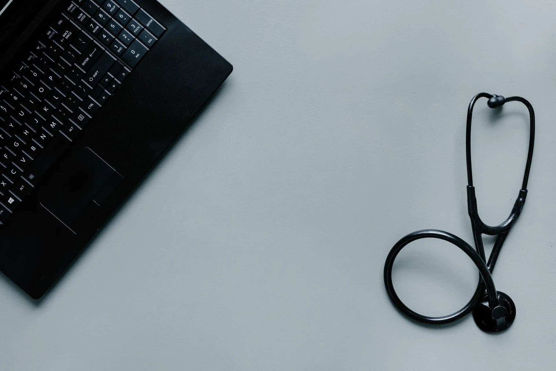 Minimalist image depicting a laptop and stethoscope representing telemedicine and digital health, illustrating Senate passes healthcare cybersecurity bill that would mandate MFA and