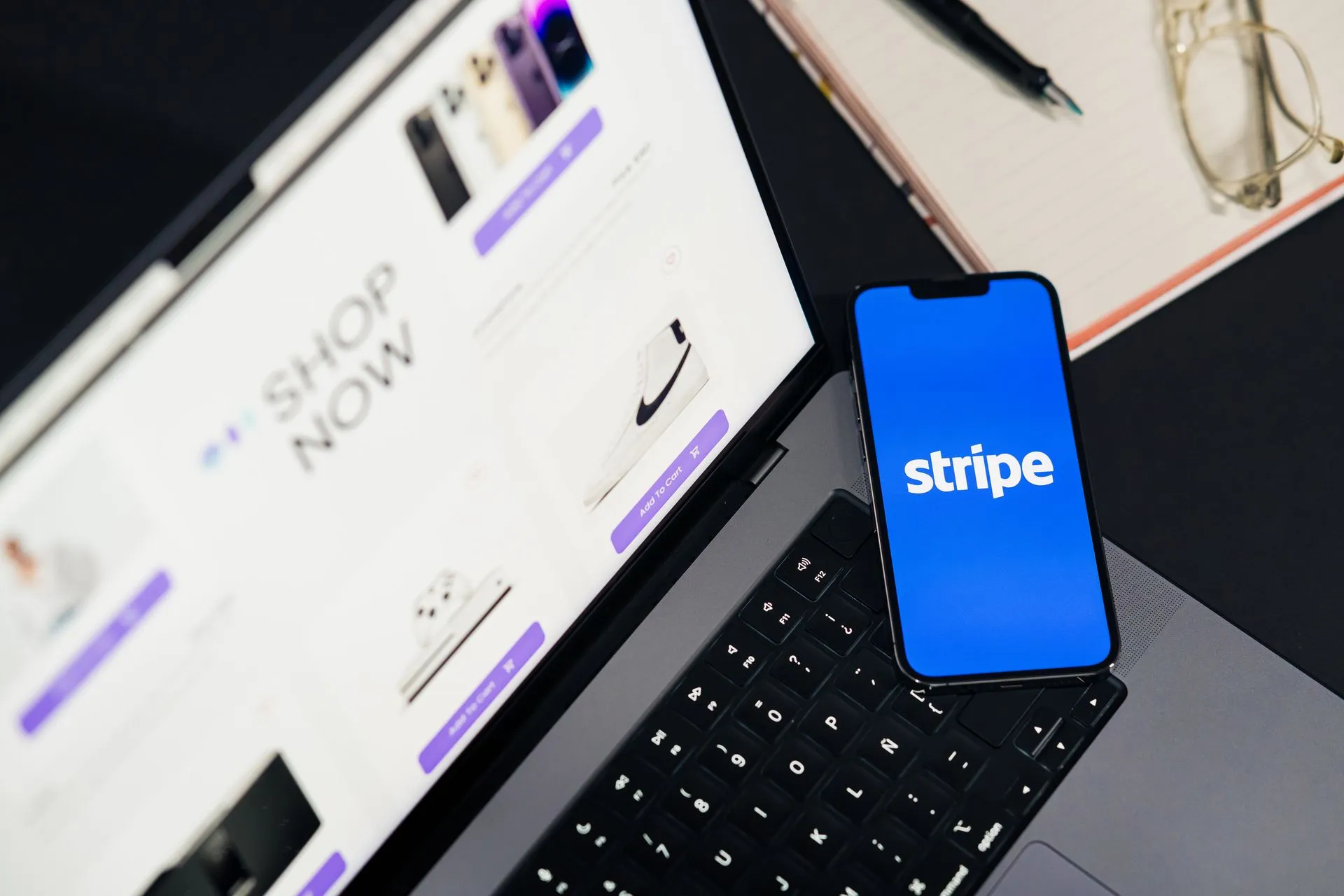 Mobile phone displaying Stripe app on a laptop with an eCommerce site open, symbolizing online shopping.