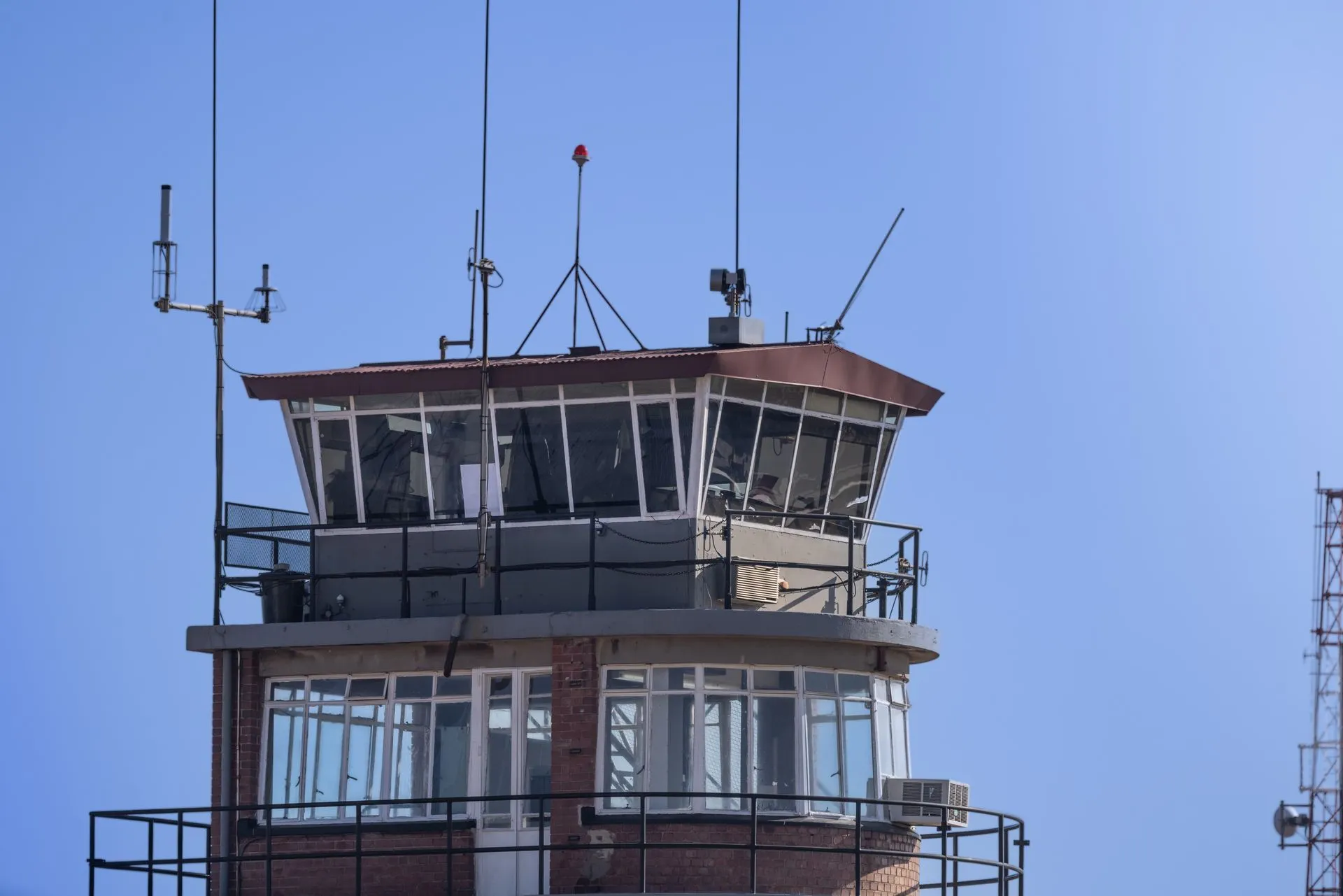 A modern airport control tower against a clear blue sky, showcasing aerial communication infrastructure, illustrating ATNS cyberattack