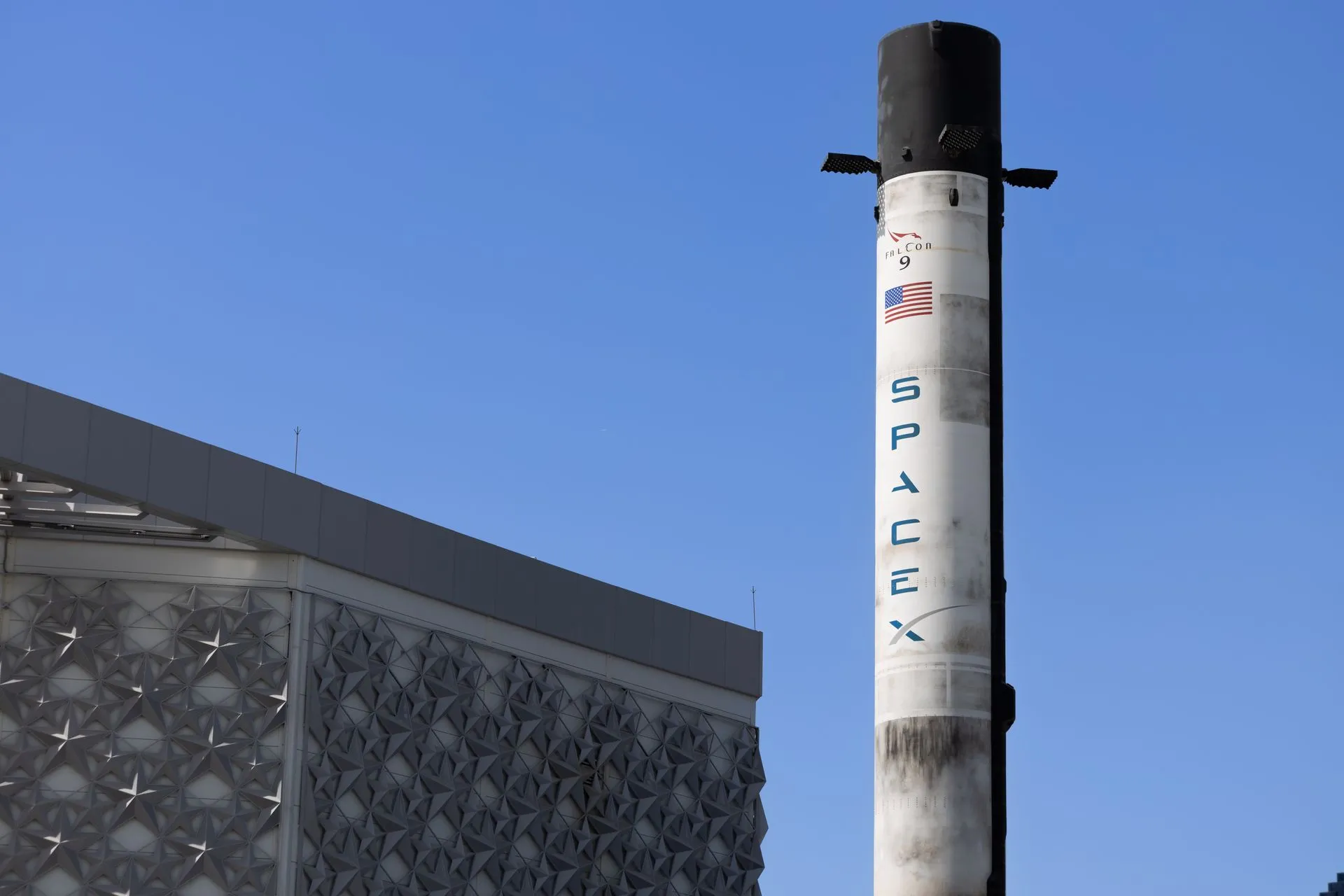 A SpaceX Falcon 9 rocket displayed outdoors against a clear blue sky in Dubai, illustrating SpaceX Starship reaches orbit for the first time and deploys 26 Starlink satellites