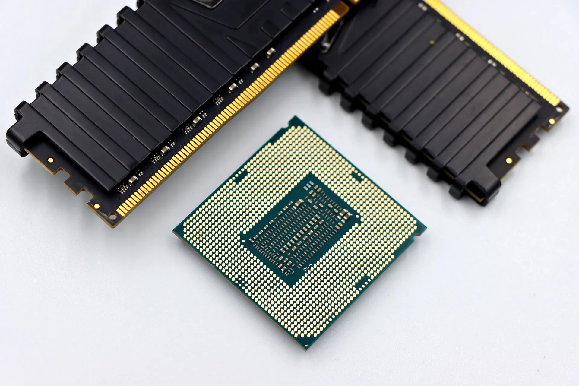 A CPU and RAM sticks displayed on a white surface, showcasing computer hardware components, illustrating Spectre BTR attack leaks Linux root password hash in minutes, even on patched