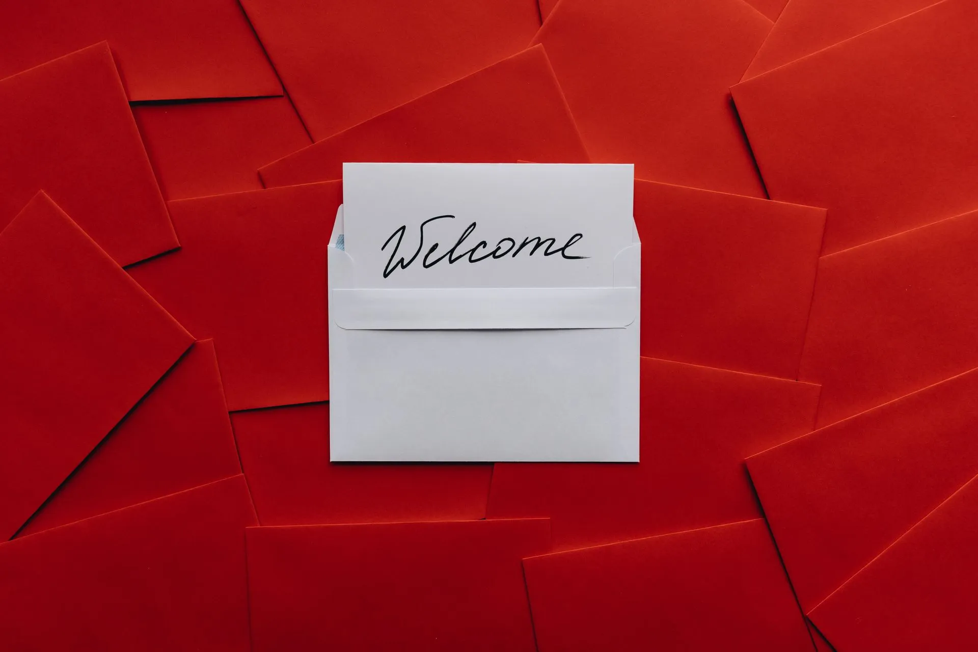 A white card with 'Welcome' text in an envelope against a red envelope background, illustrating Russia's Star Blizzard targeted 100+ organizations with fake event invites and notices