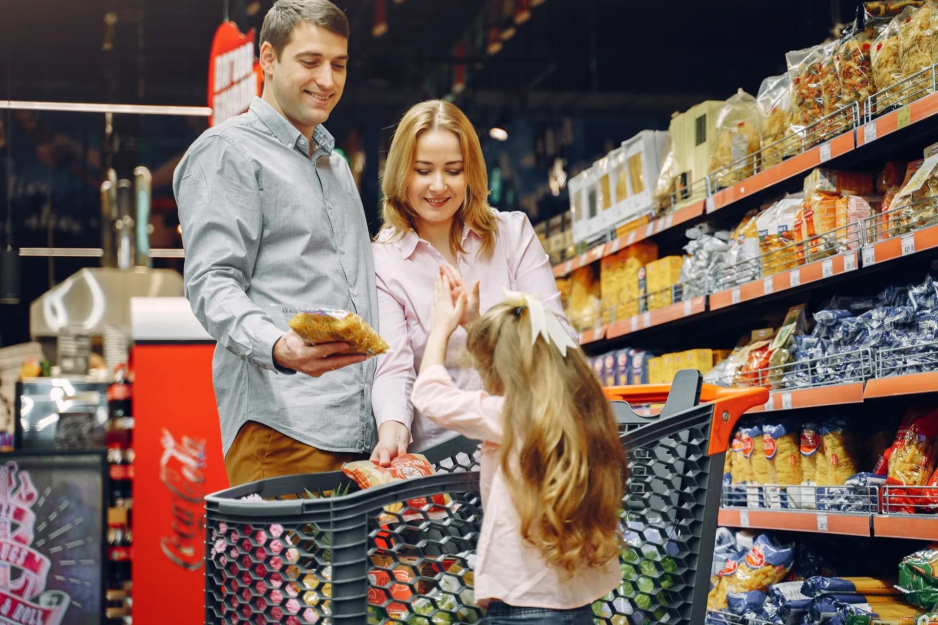 A happy family shopping together in a supermarket aisle, sharing a joyful moment, illustrating Teads Koddi partnership brings programmatic buying to retail media sponsored product ads