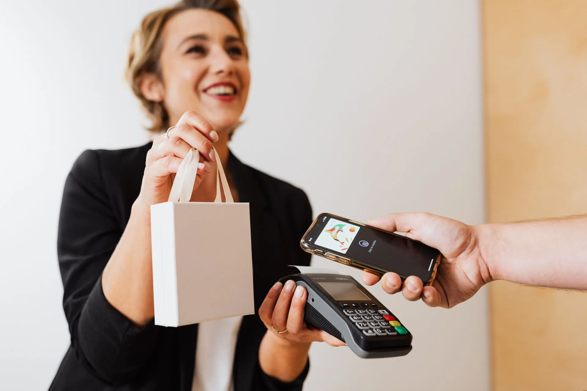 Smiling cashier handles a purchase with a contactless mobile payment in a modern shop, illustrating TikTok Shopping Assistant and one-click Buy Direct checkout let brands sell in the