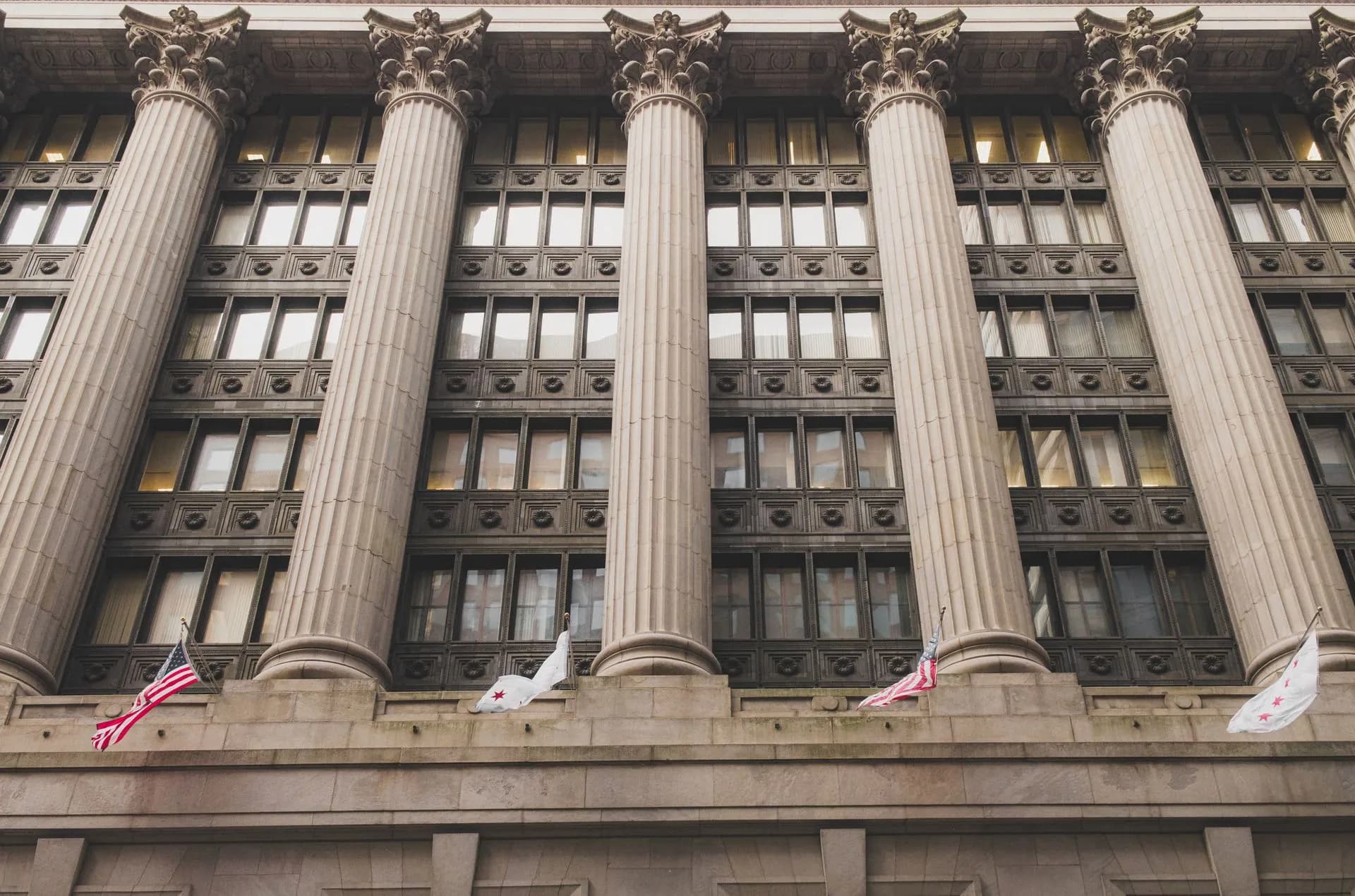 Elegant neoclassical facade with columns and flags in downtown Chicago, illustrating Trump's Super Intelligence executive order tells agencies to stop using the term 'AI'