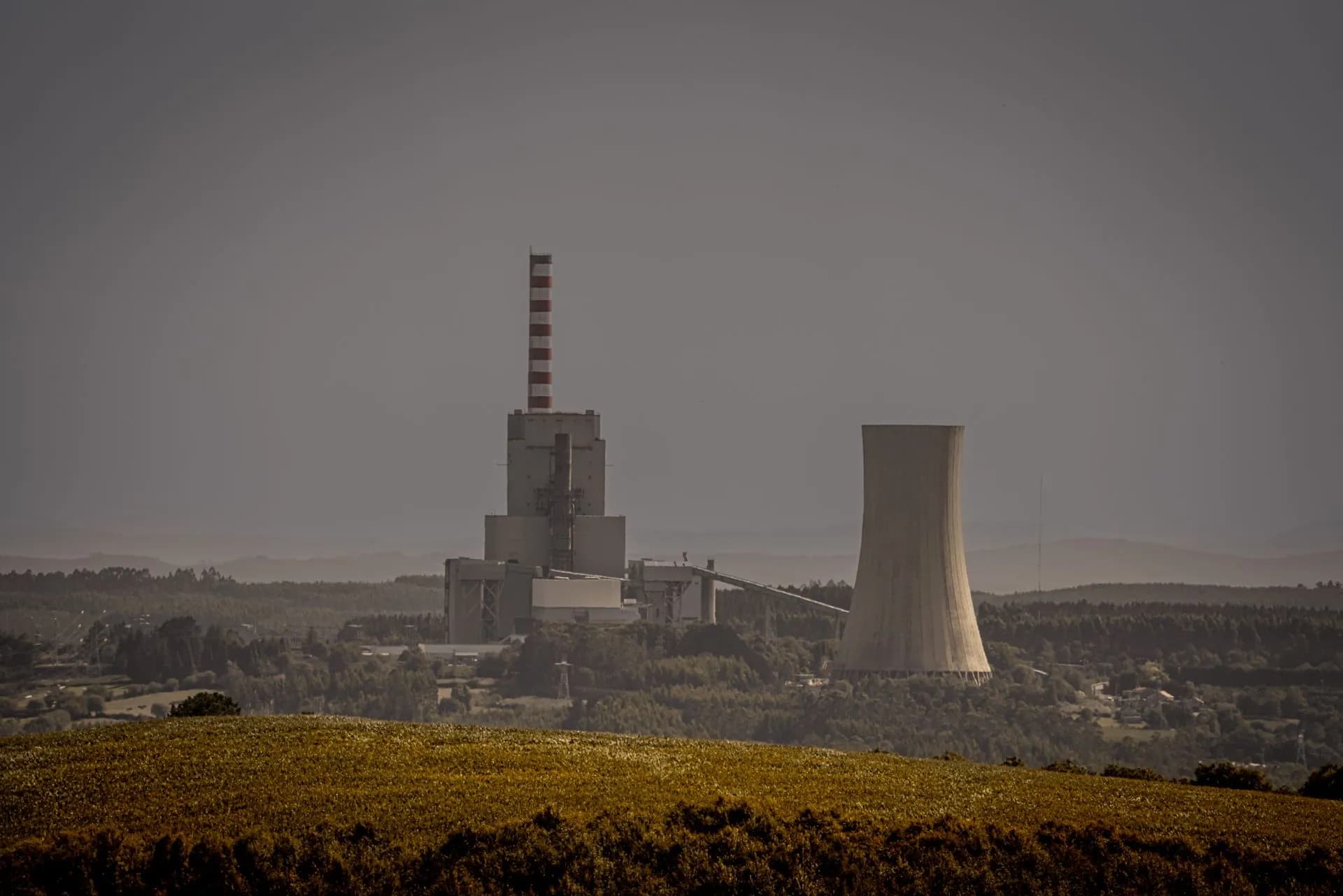 Distant view of a power plant with cooling towers amidst a vast landscape, illustrating energy production, illustrating Type One Energy raises $200M Series B to build a 400MW fusion