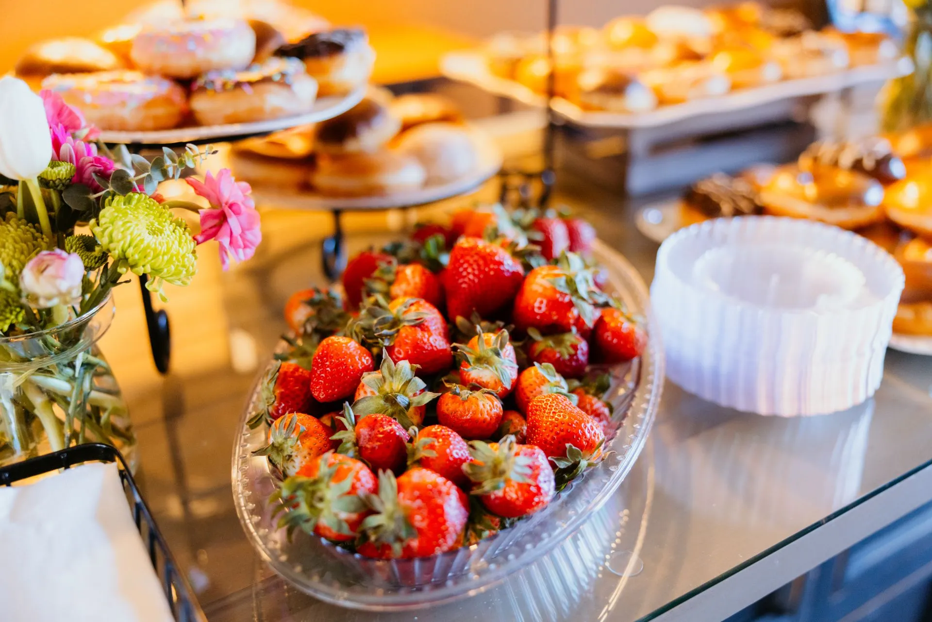 A colorful buffet spread featuring fresh strawberries, donuts, and floral decorations, illustrating Uber to buy ezCater for $2.3 billion in cash to move into corporate catering
