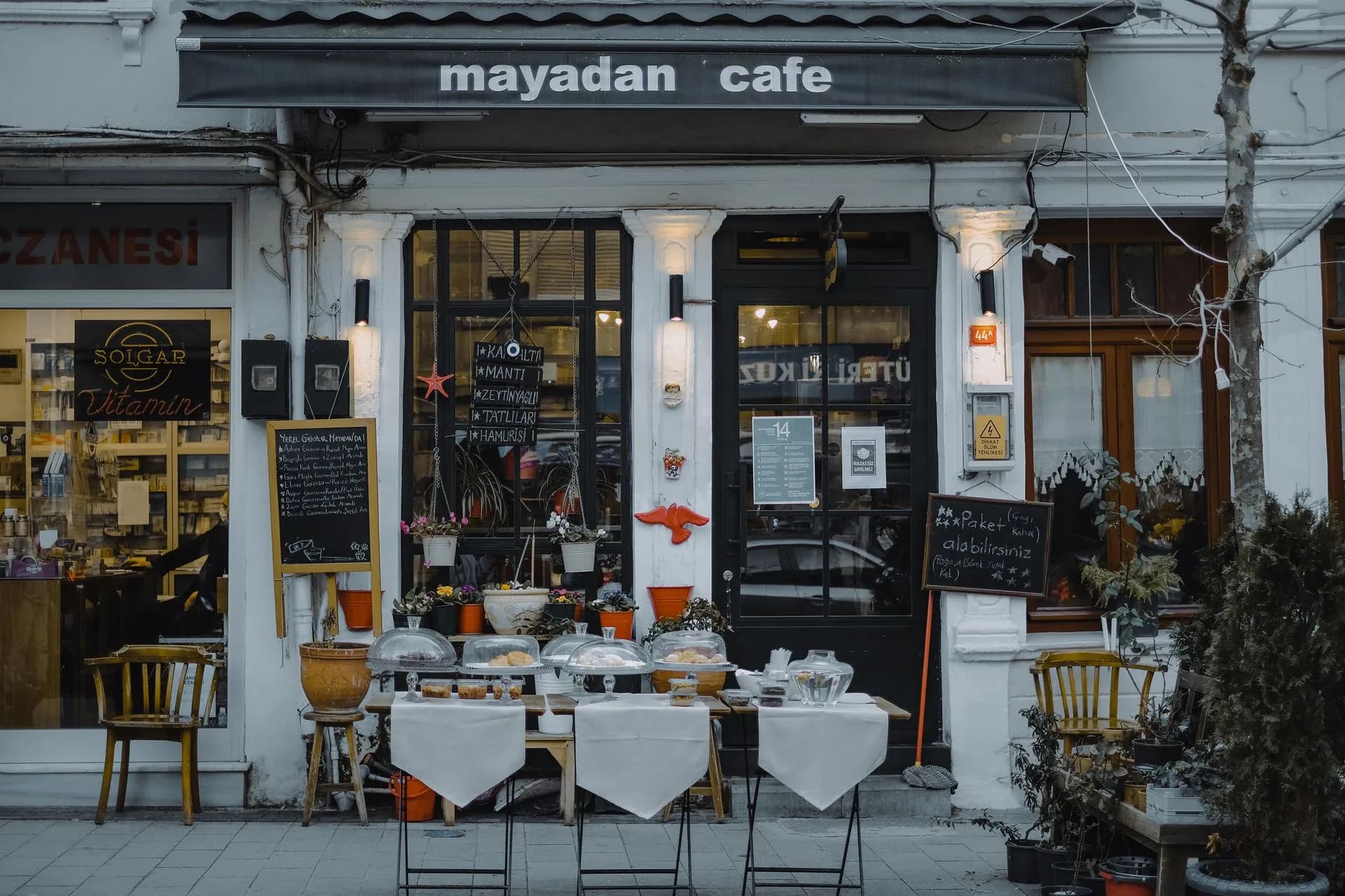 An inviting outdoor café showcasing local food, menu boards, and charming decorations in a quaint neighborhood setting, illustrating Valley National agrees to $340 million Bluevine acquisition